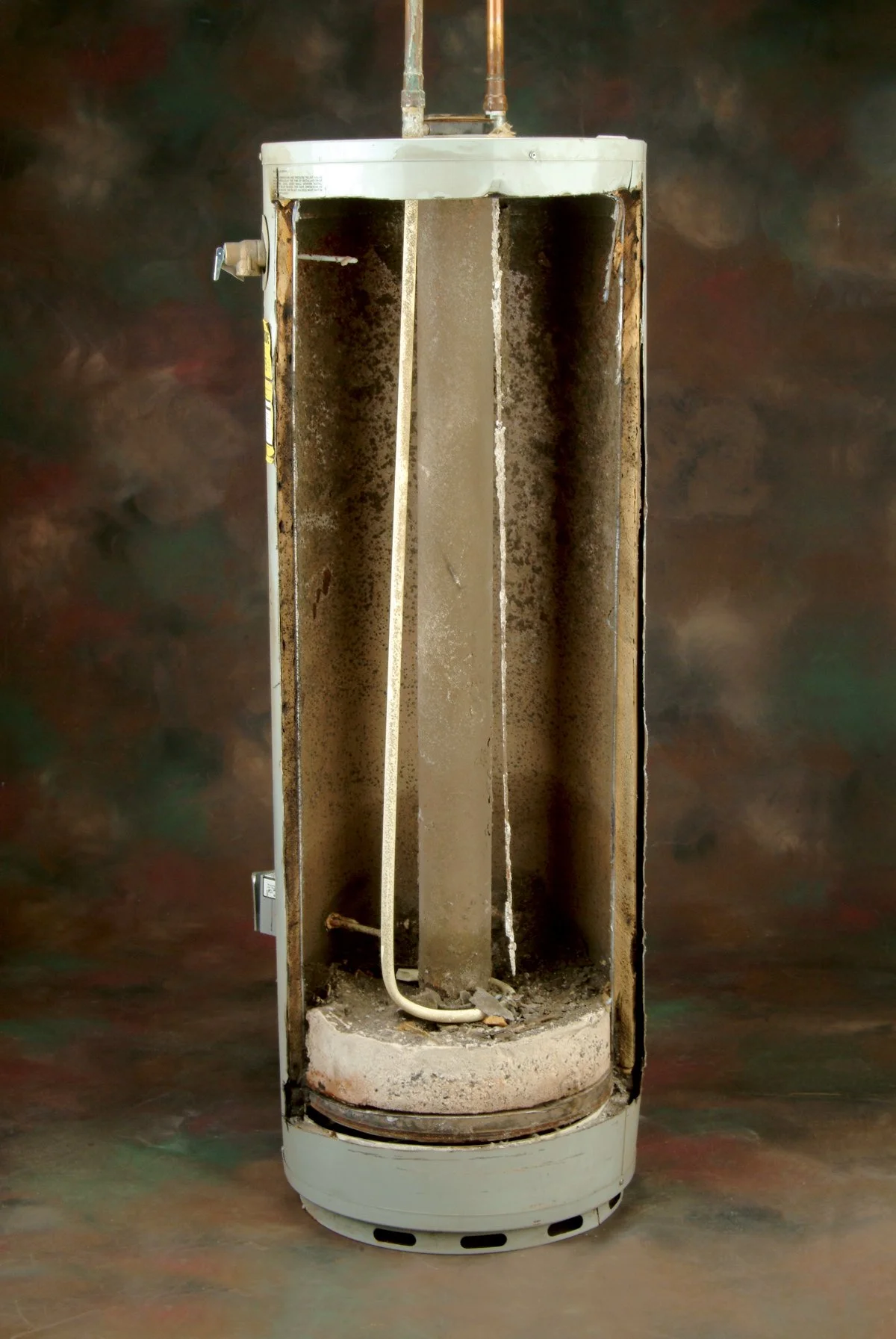 A rusty and partially disassembled old shower stall with dirt, grime, and corrosion, and exposed pipes.