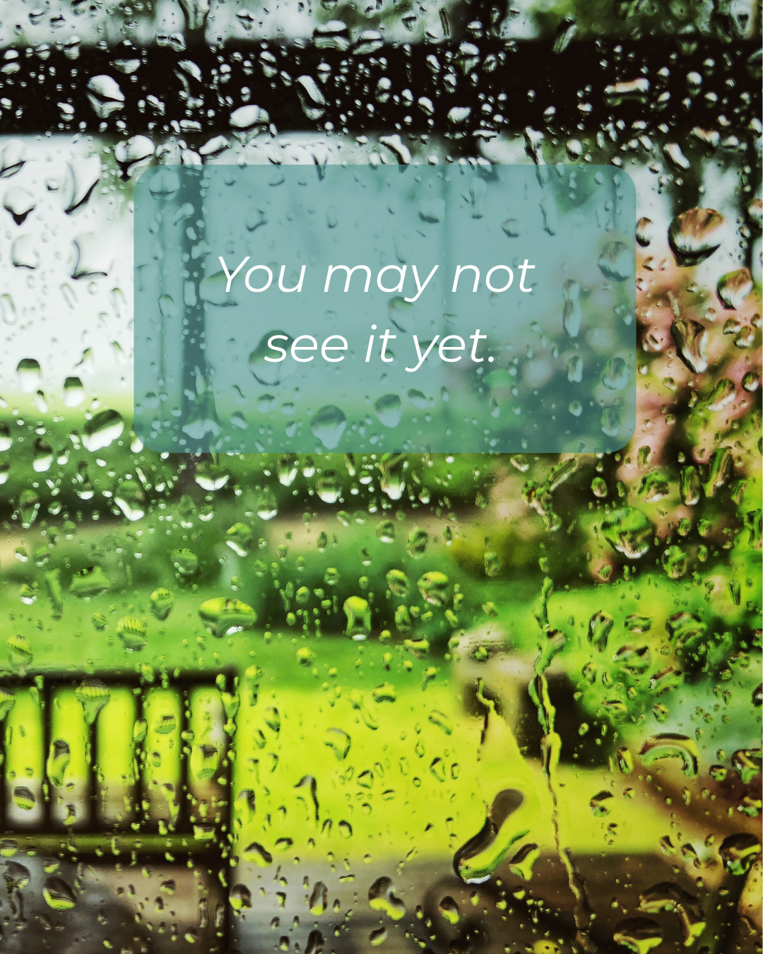 A window with rain droplets on it, showing a blurred green outdoor scene with trees and a fence. Overlay text reads, "You may not see it yet."