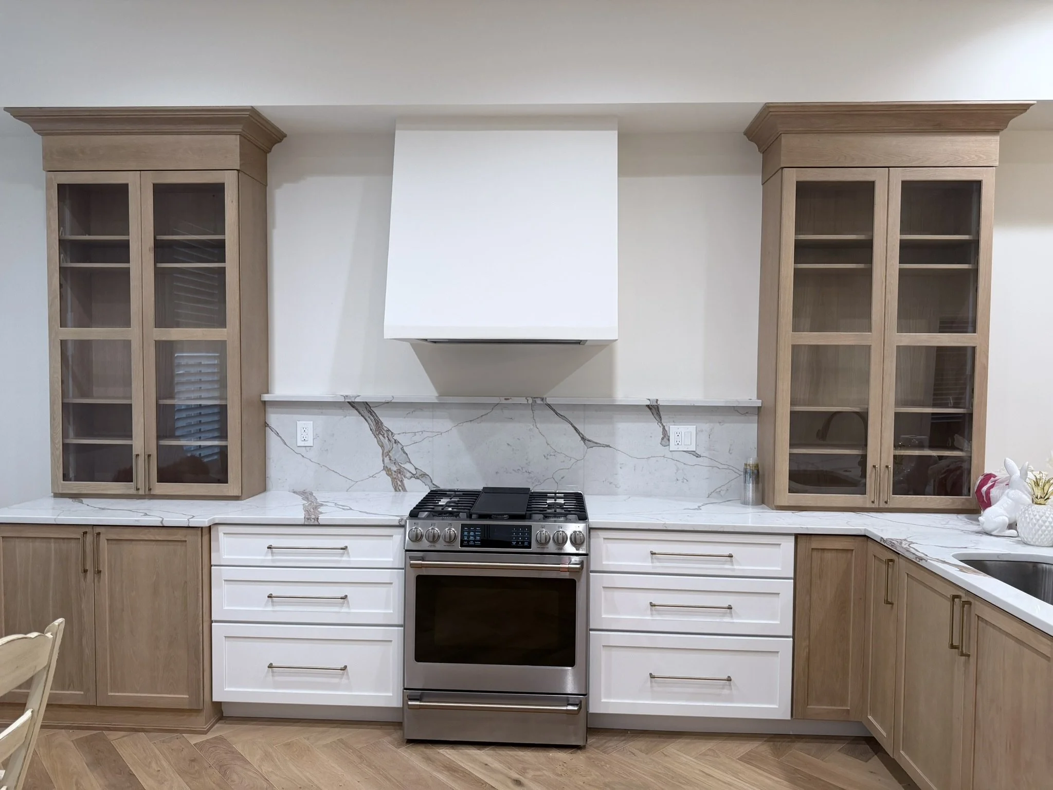 Kitchen with white and wood cabinetry, marble backsplash, and stainless steel stove.