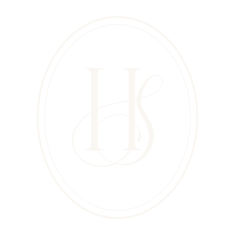A black background with a white oval border and the letters H and S monogrammed in the center placed inside a smaller oval border.