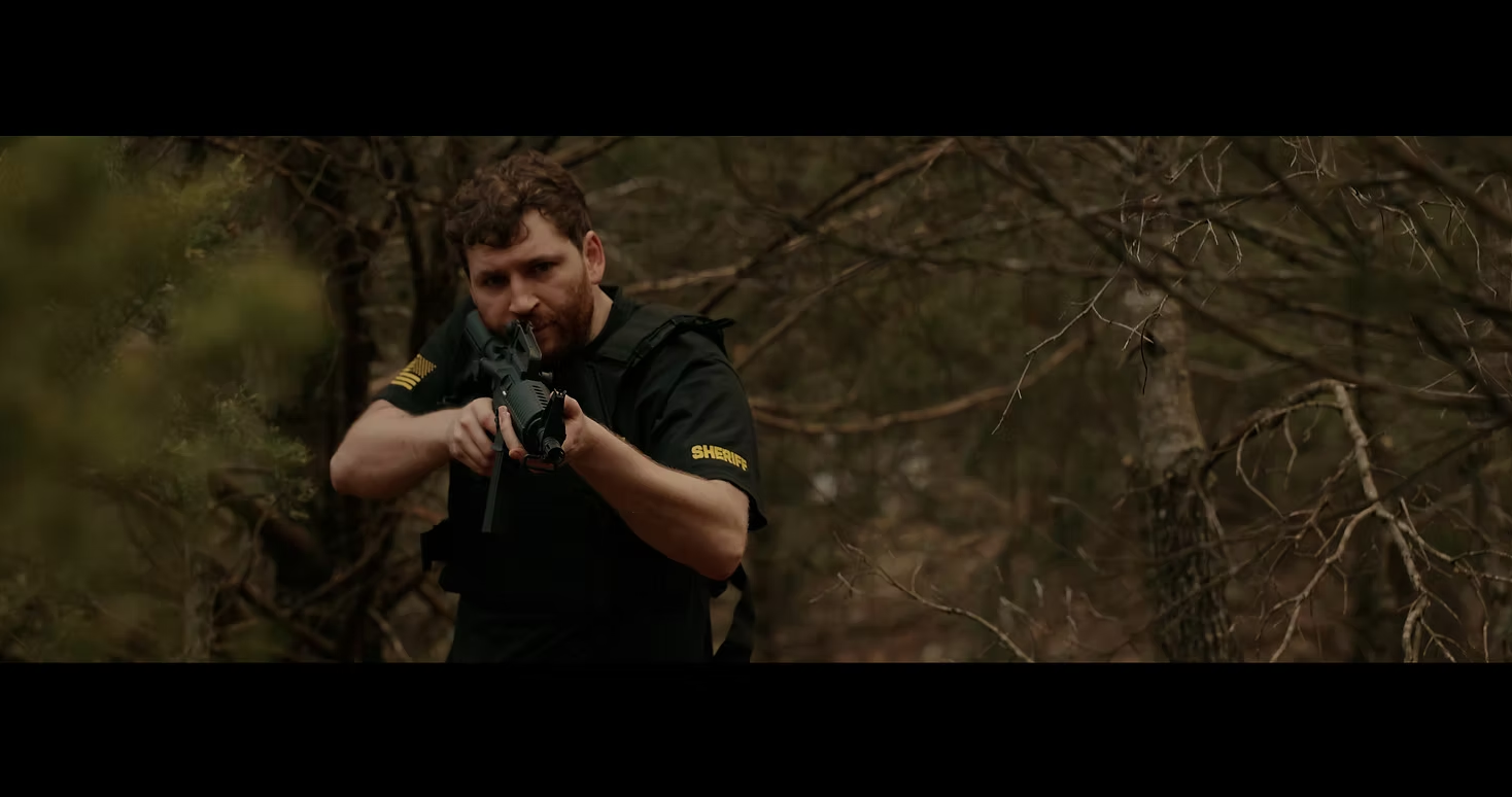 A redheaded man holds a gun