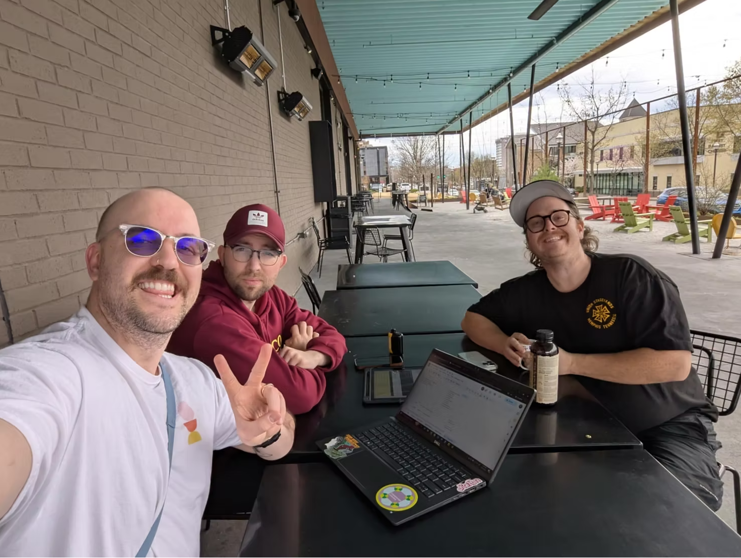 Three men smile while sitting at a picnic table