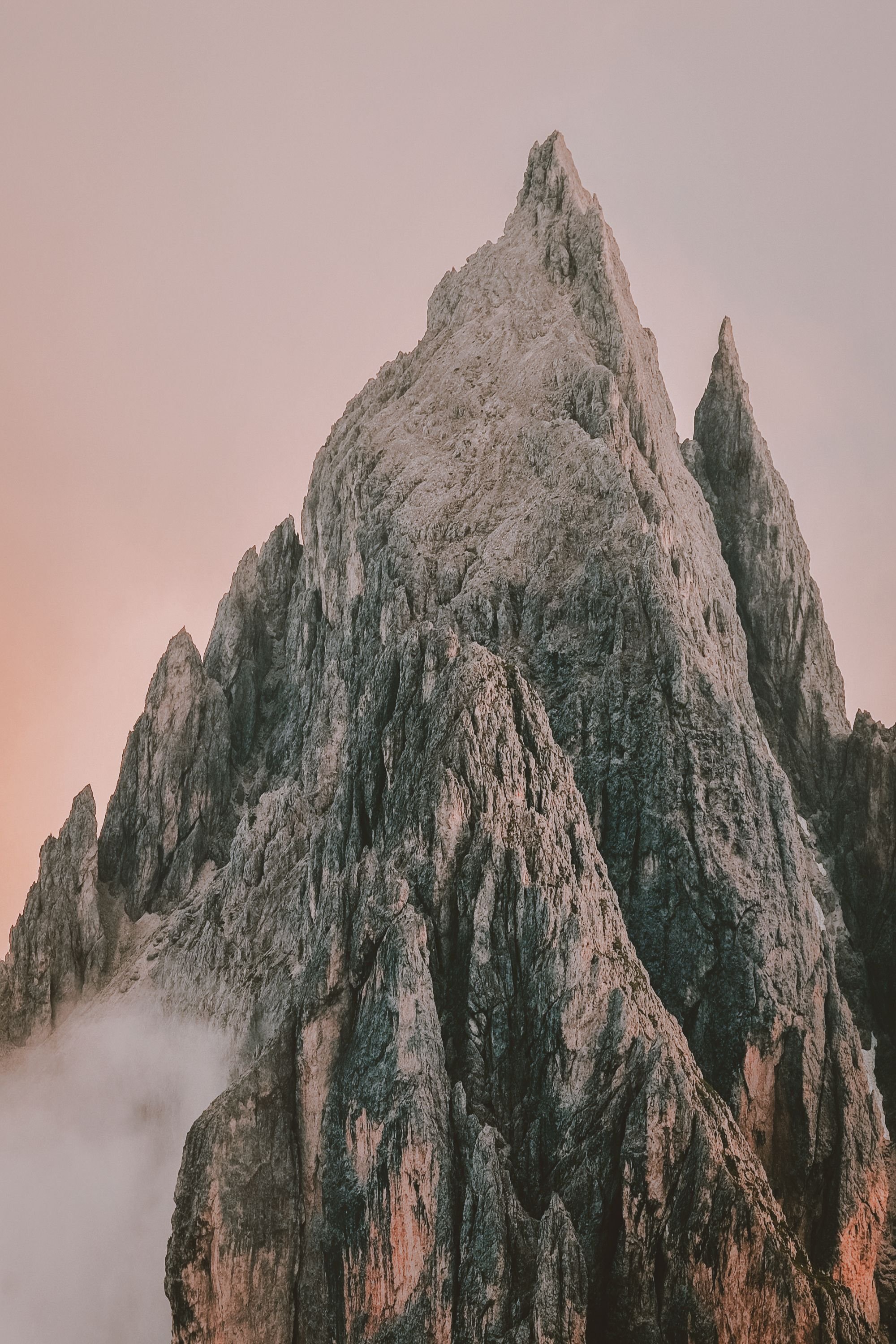 A snowy mountain with a pink sky background