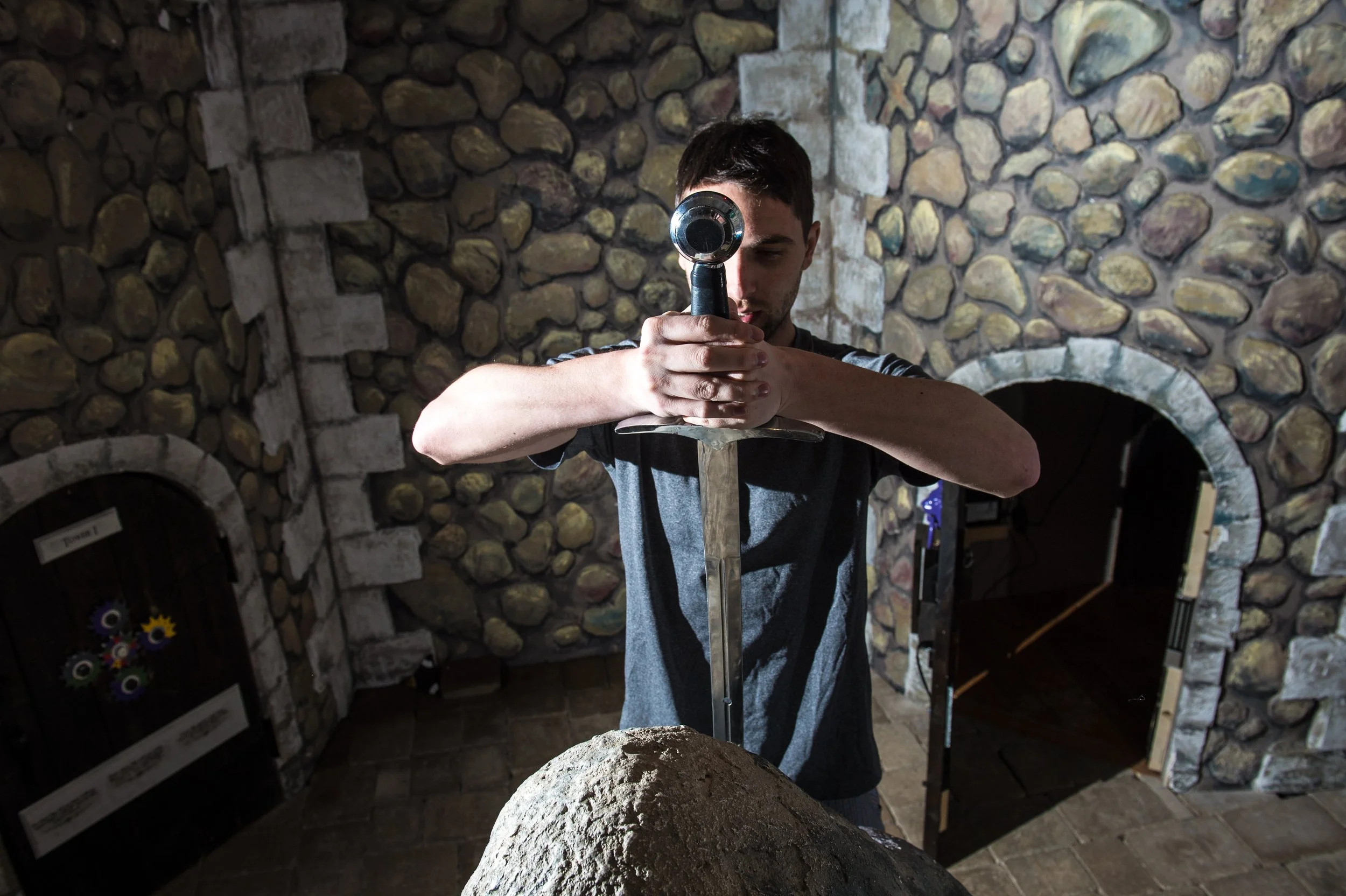 A young man pulling a sword from a stone with a castle in the background