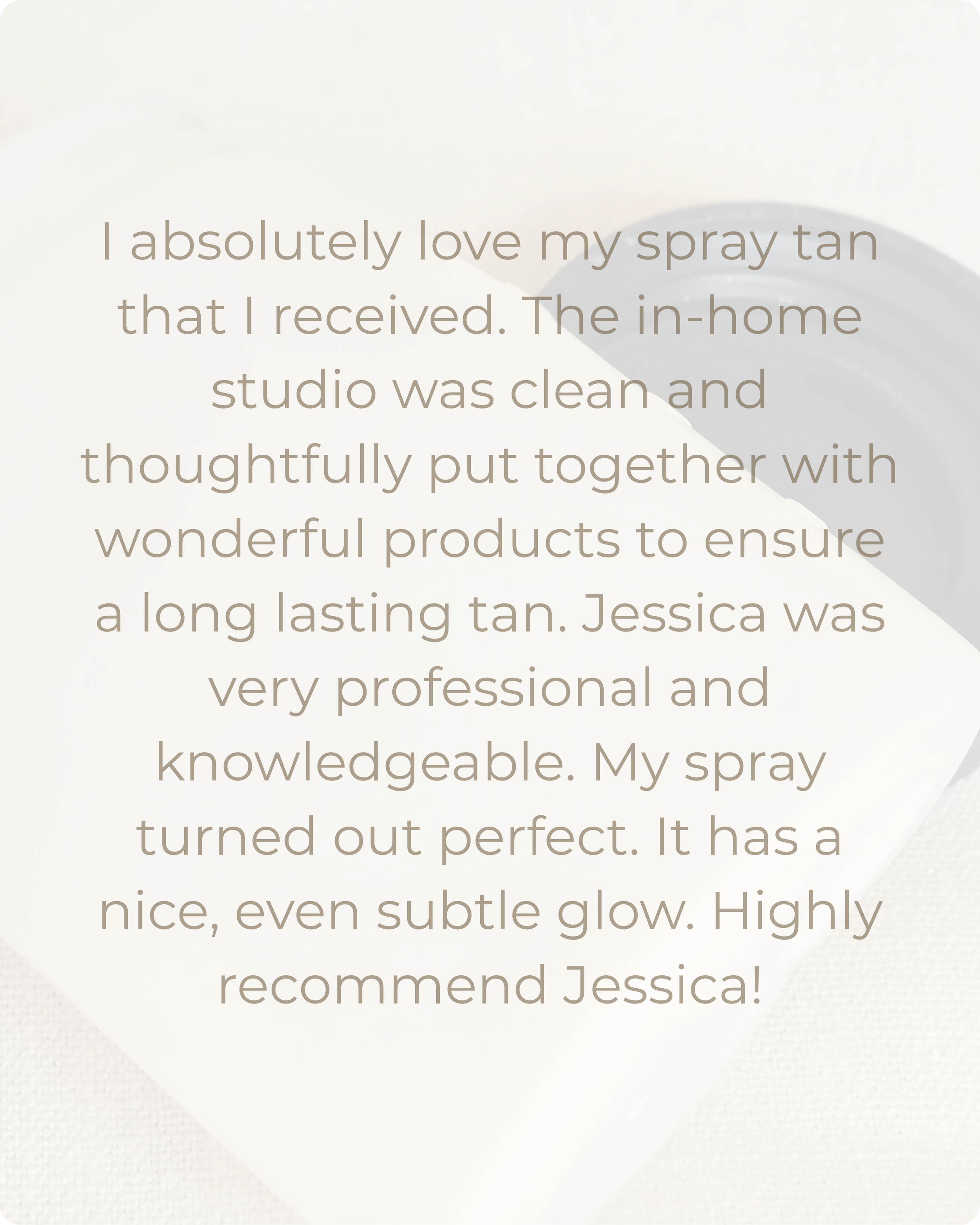 Close-up of a white spray tan bottle with a black spray nozzle, placed on a beige textured fabric background.