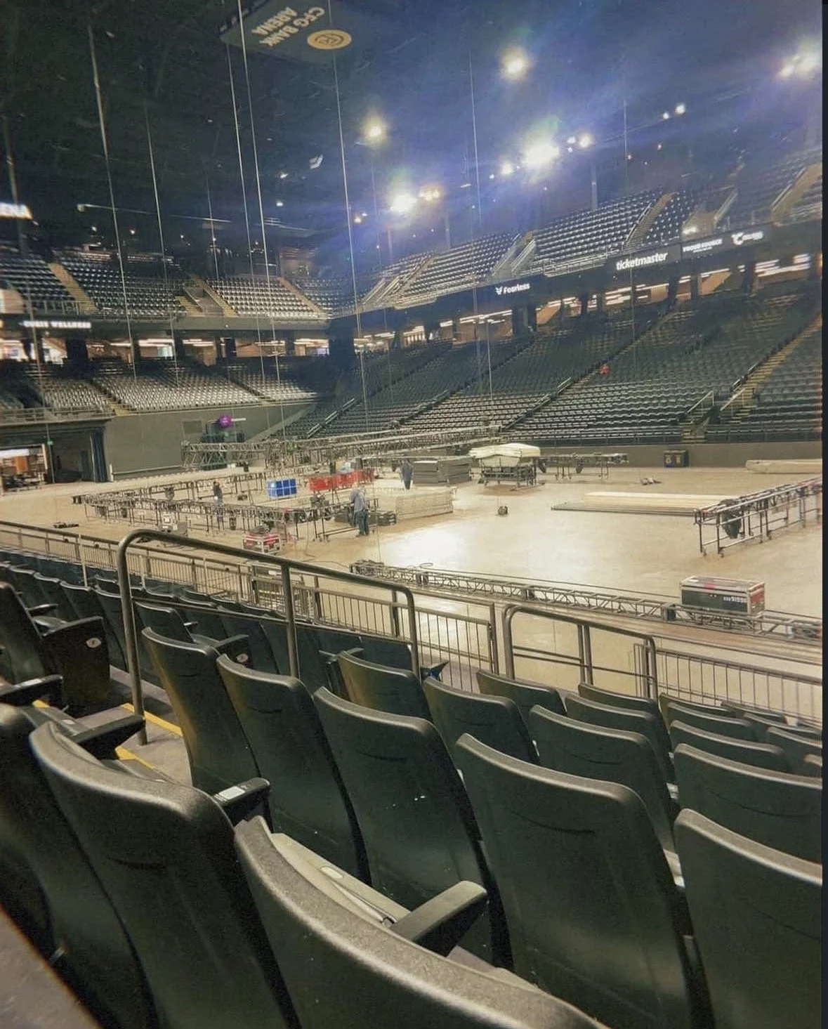 Empty indoor arena with rows of empty seats, stage equipment, and production equipment.