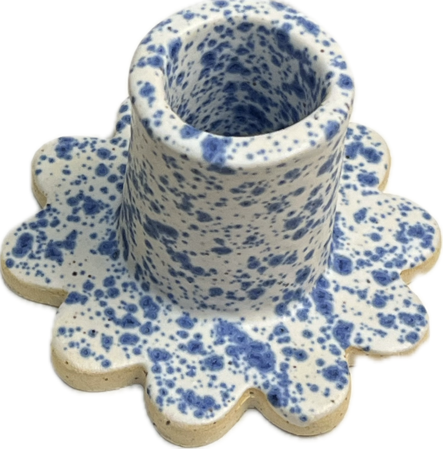 A ceramic cup with blue speckled pattern, placed on a matching flower-shaped ceramic plate with the same pattern.