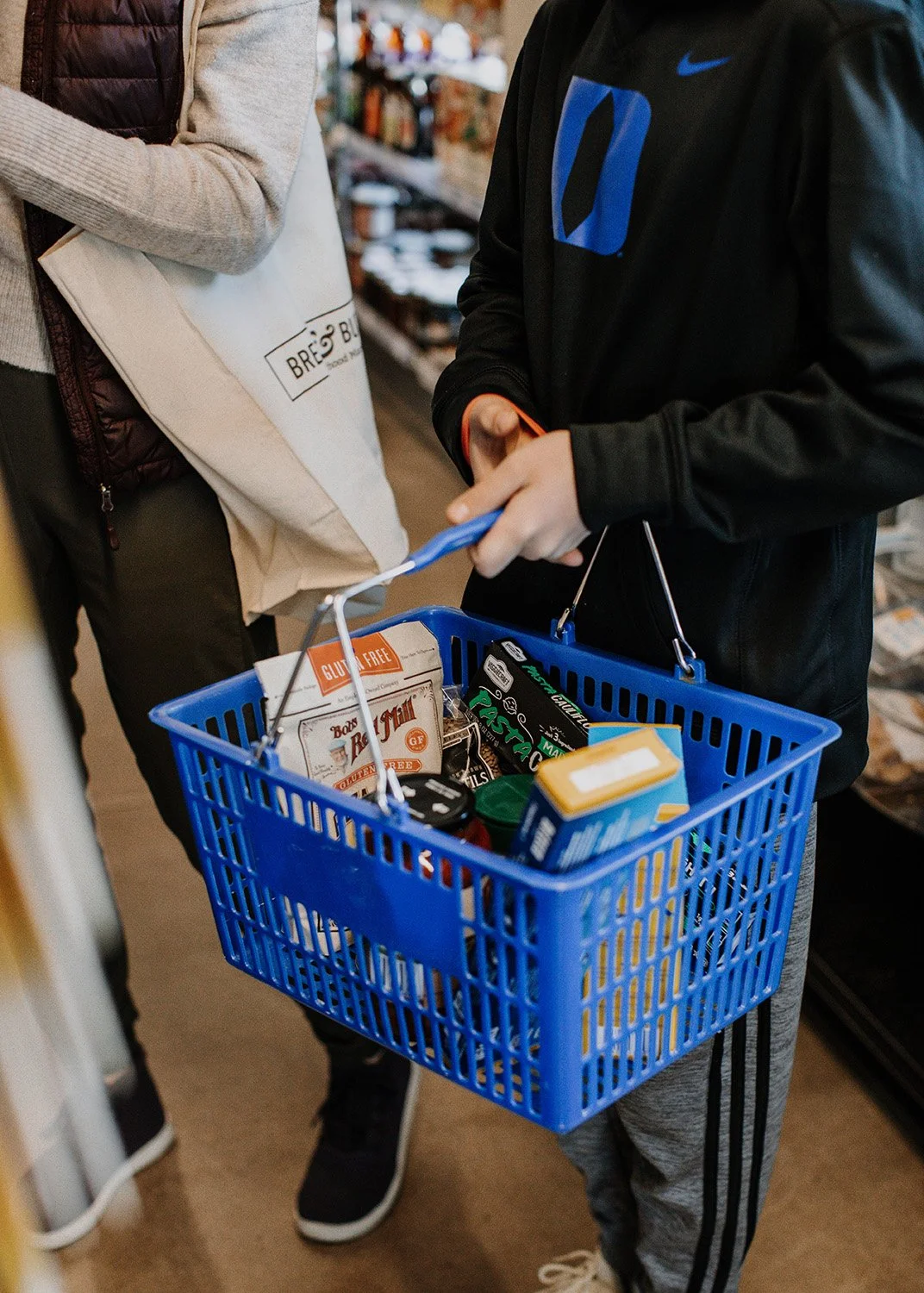 A young person holding a bread and butter shopping basket.