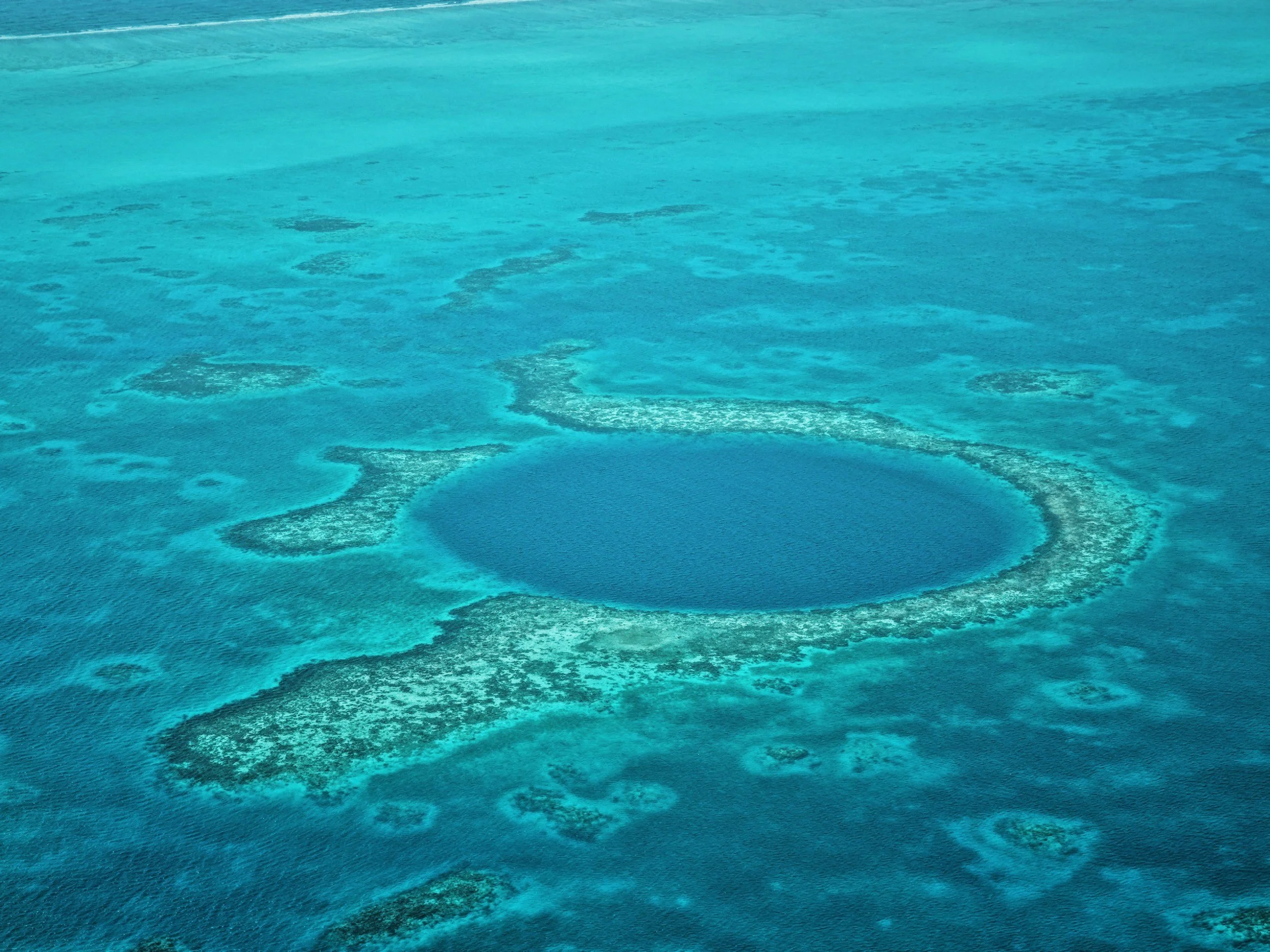 Aerial view of a turquoise coral reef or atoll in a clear blue ocean.