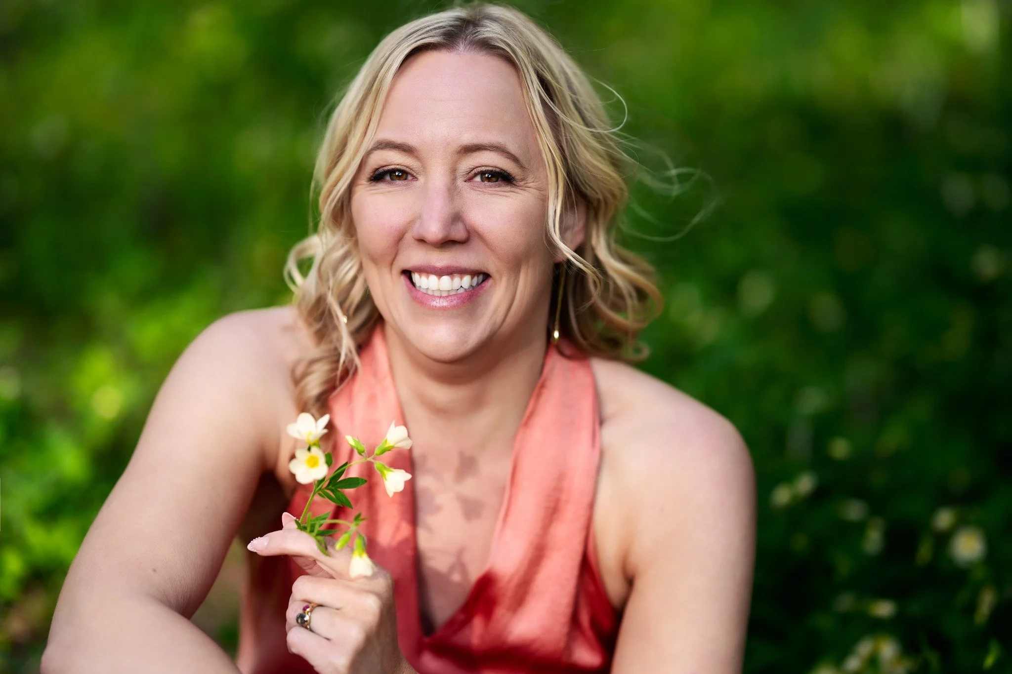 Karen Bommentre, LMFT, smiling outdoors in a coral dress at Wild Gem Therapy.