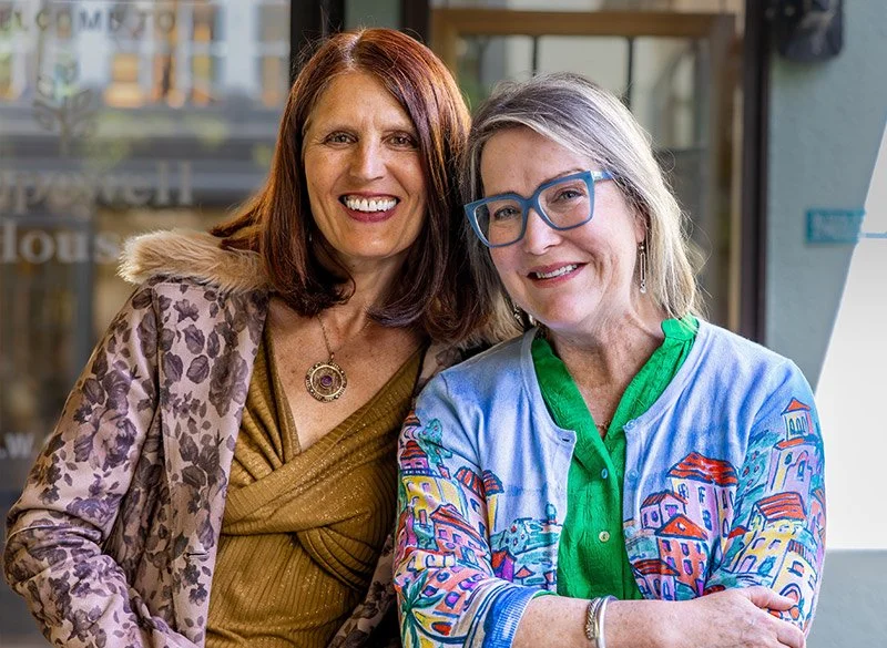 Theresa Trelstad with her friend wearing colorful clothing standing close together at a Pairs or Friends Reiki Session.