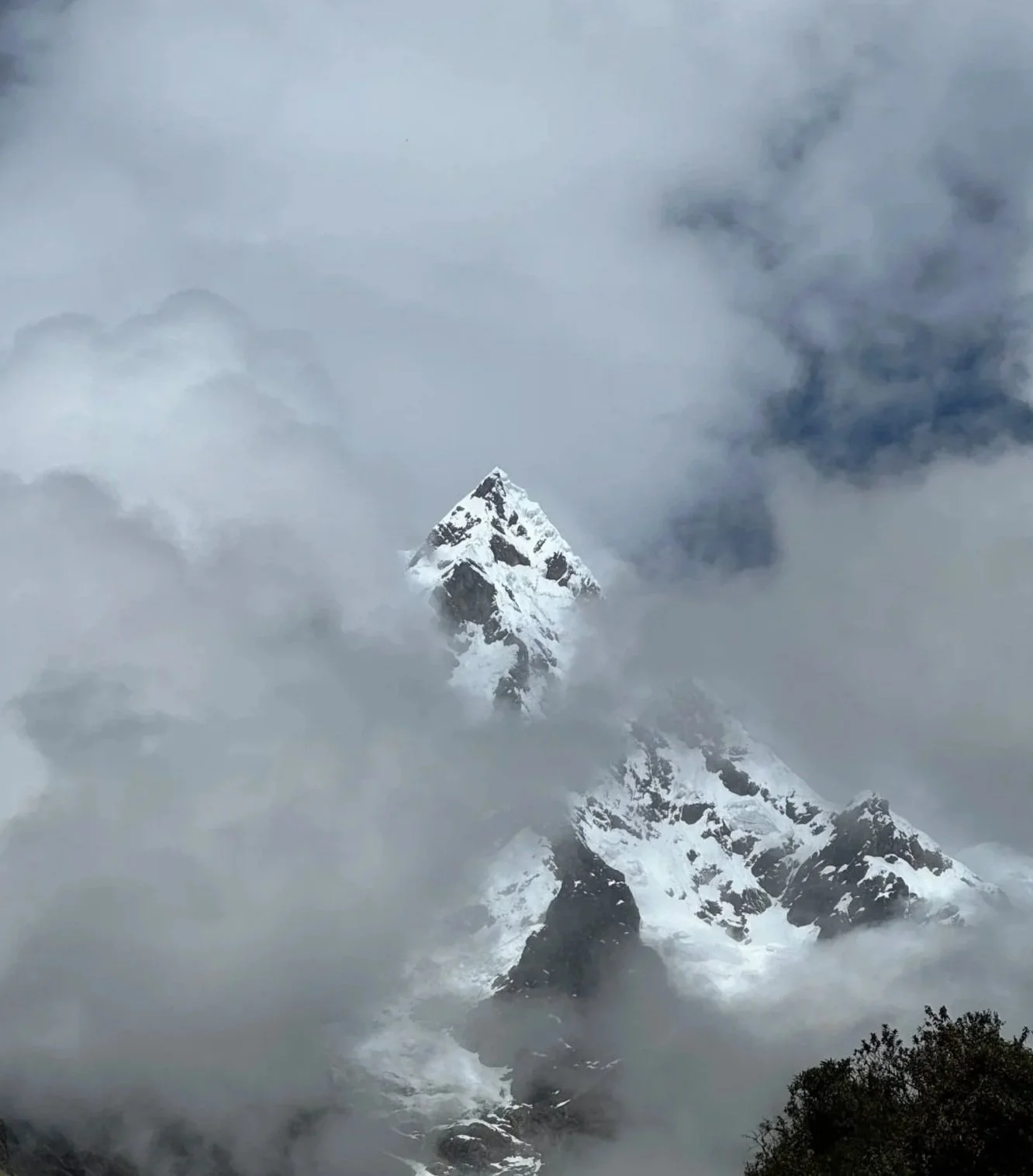 Snow-covered mountain peak emerging through clouds and mist.