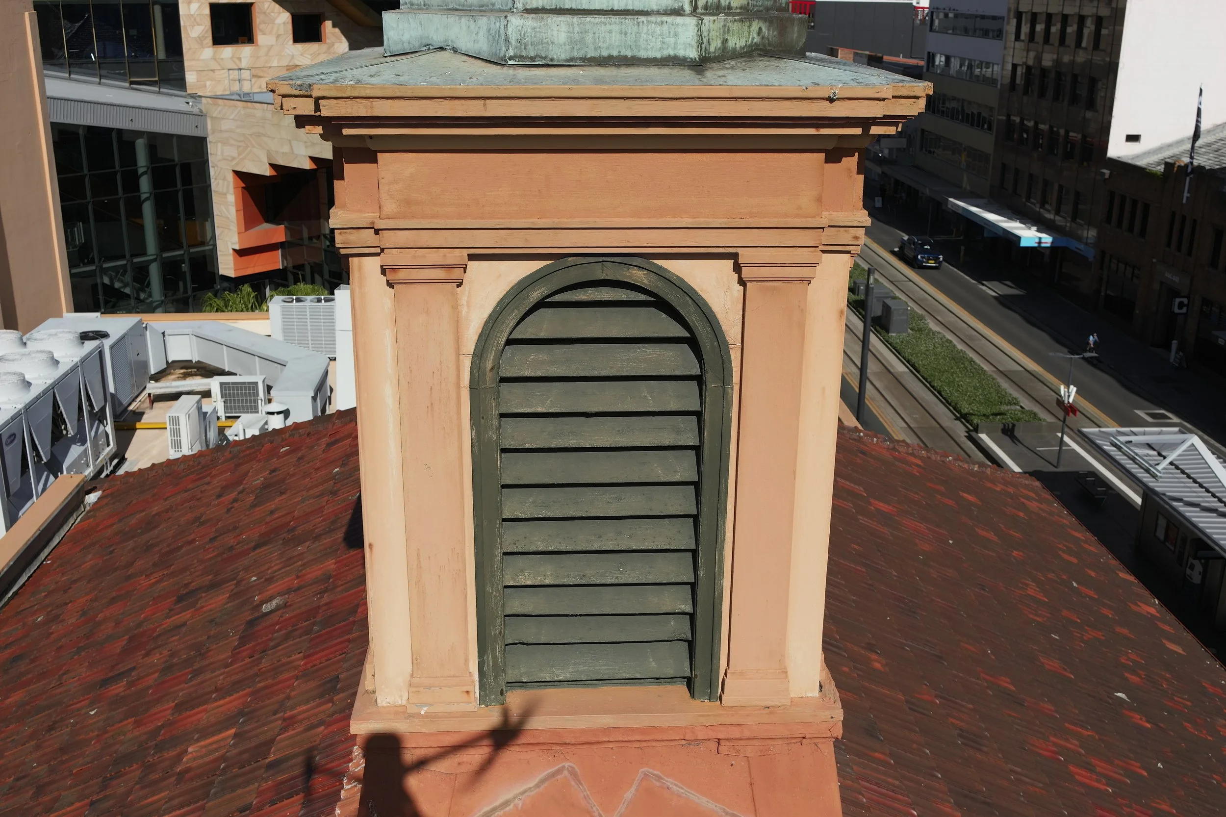 Close-up of a building's rooftop ventilation area with a chimney and a city street in the background.