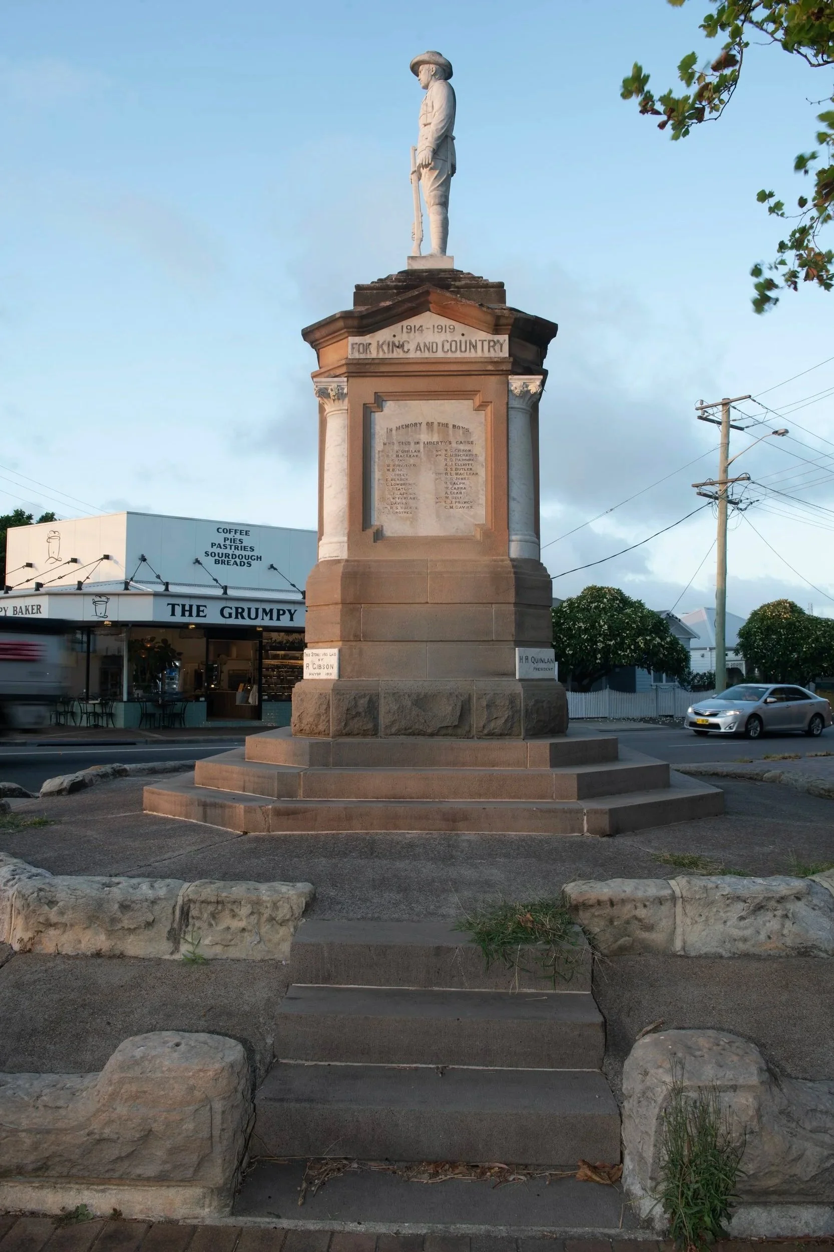 A war memorial monument dedicated to those who served in World War I from 1914 to 1919, featuring a white statue of a soldier in uniform, holding a rifle, atop a stone pedestal with inscribed text, located outdoors on a city street.