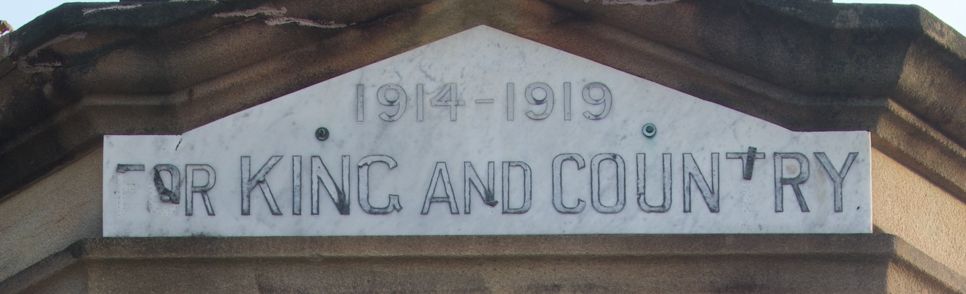 A historical plaque with the years 1914-1919 and the inscription 'FOR KING AND COUNTRY' mounted on a stone building.