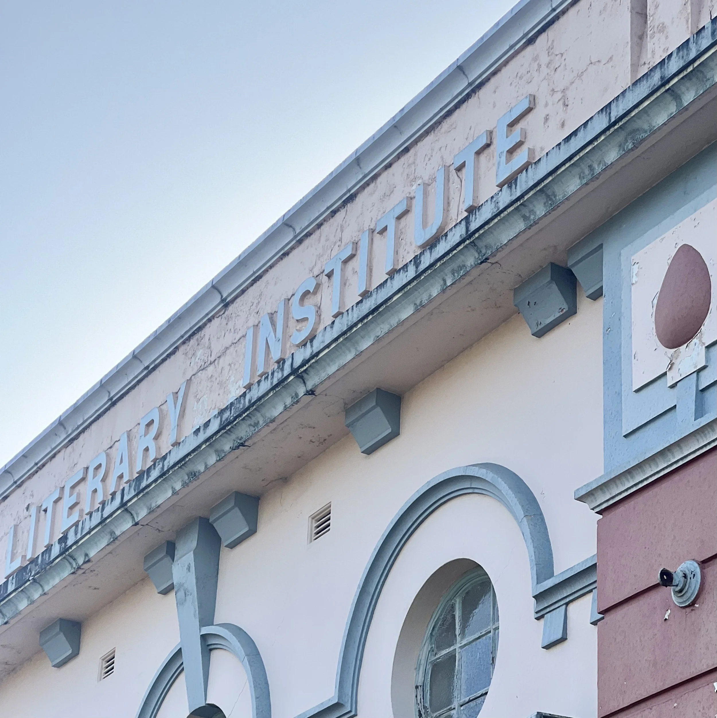 Close-up of a building's facade with architectural details and partially visible lettering on the wall.