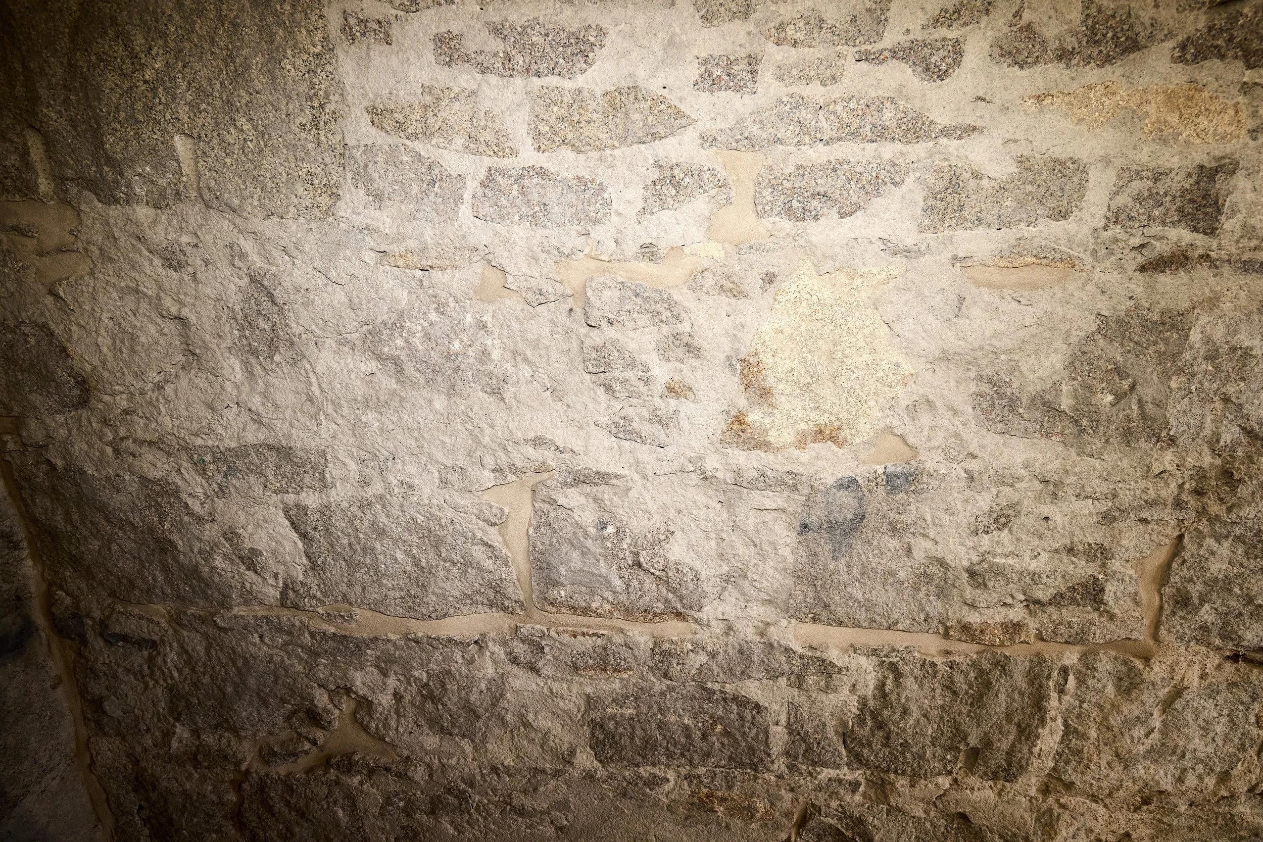 Close-up of a stone wall with rough, uneven stones and mortar.