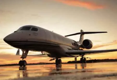 Private jet on airport tarmac at sunset.