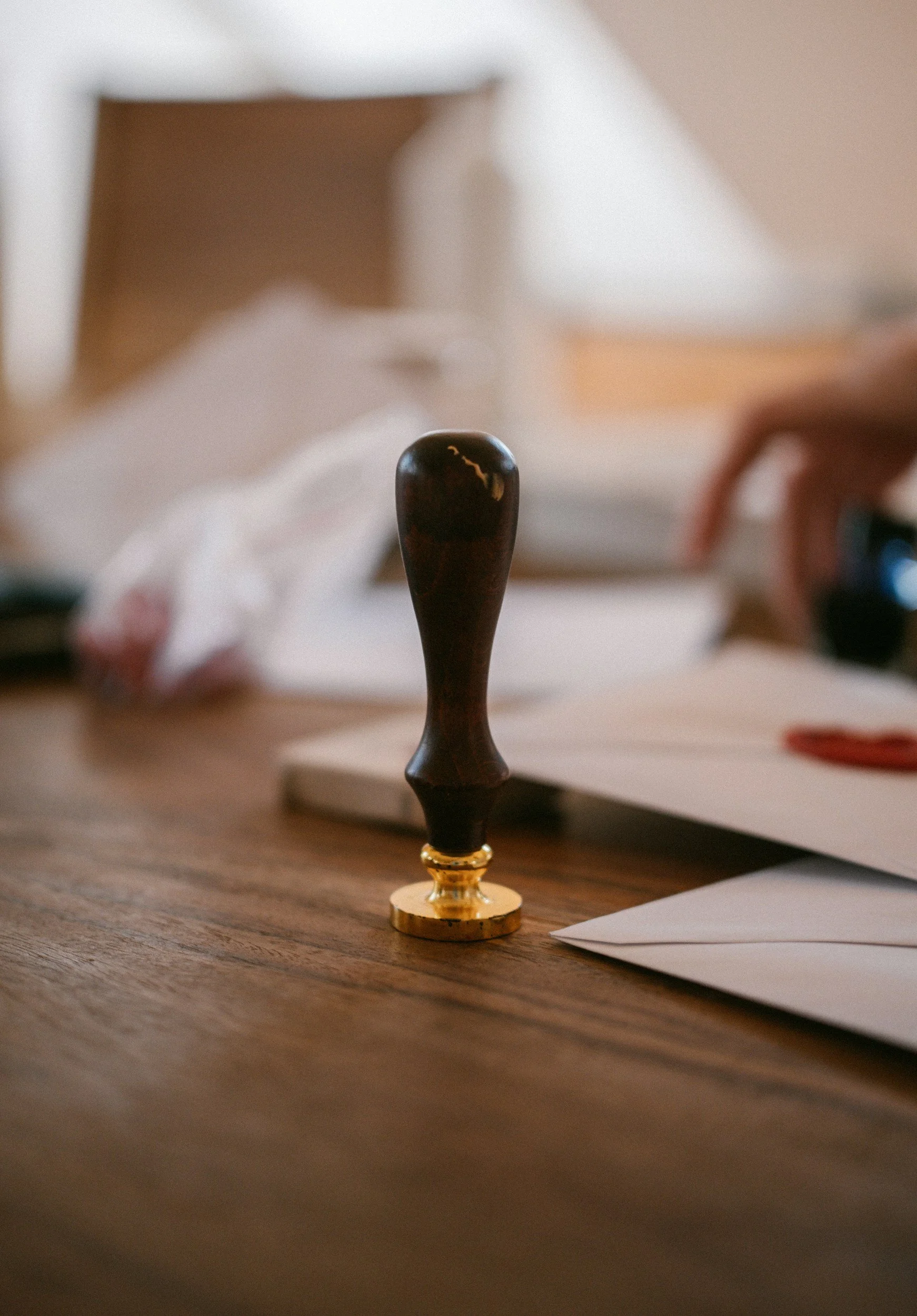 Close-up of a chess pawn standing on a wooden table with some papers and a blurred background.