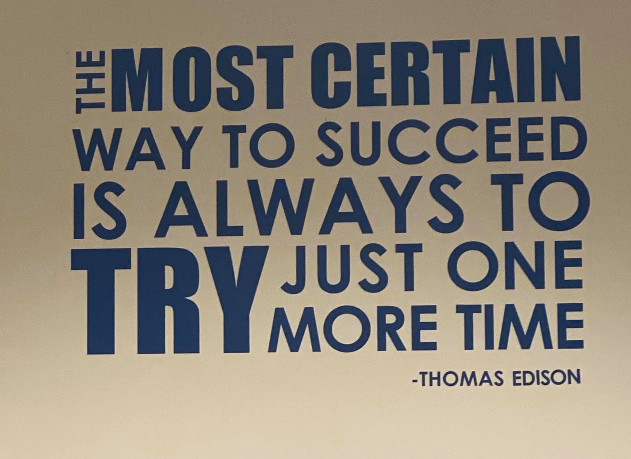 Quote by Thomas Edison about success and perseverance on a beige wall, with large blue text.