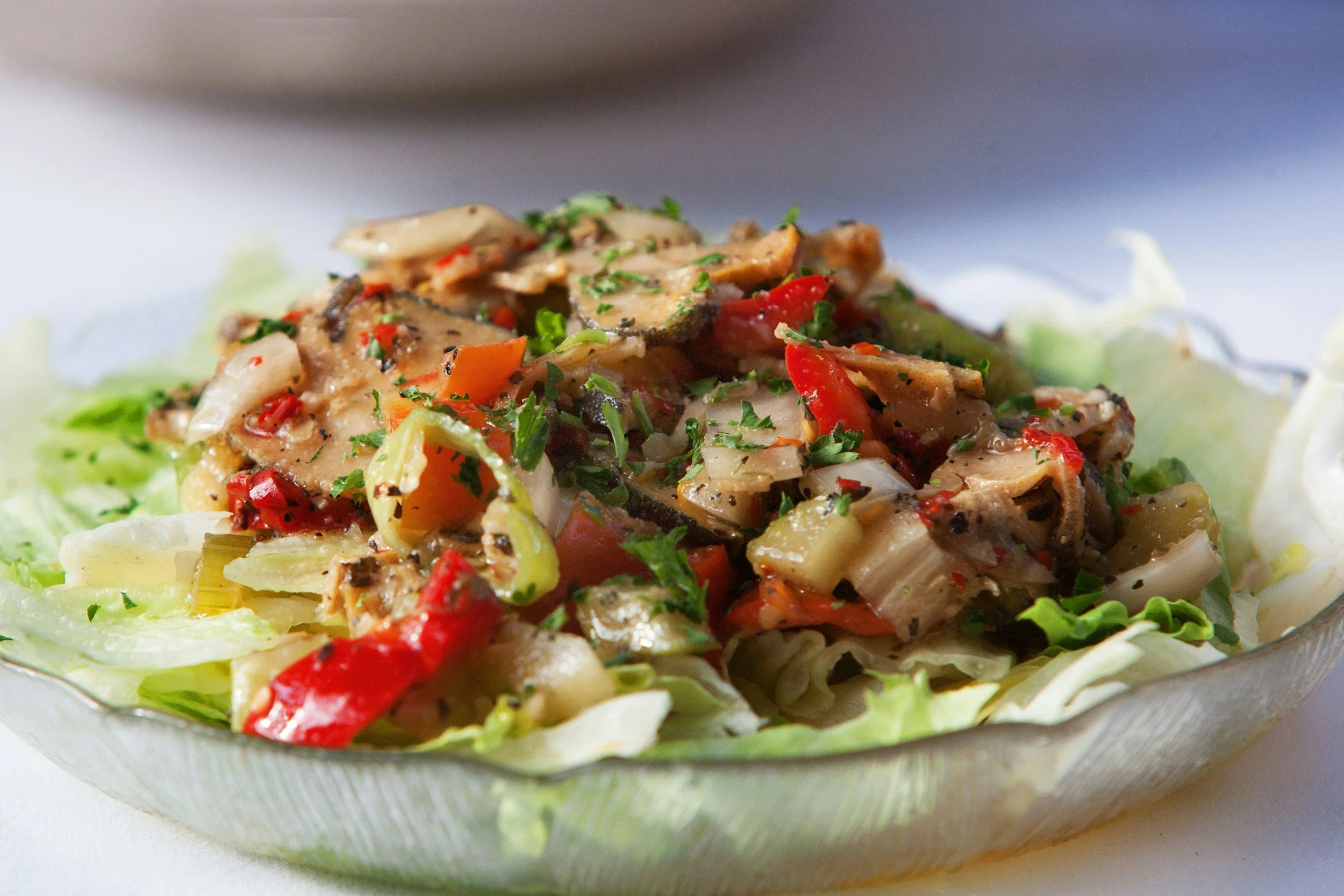 Salad with grilled vegetables and herbs on a glass dish.