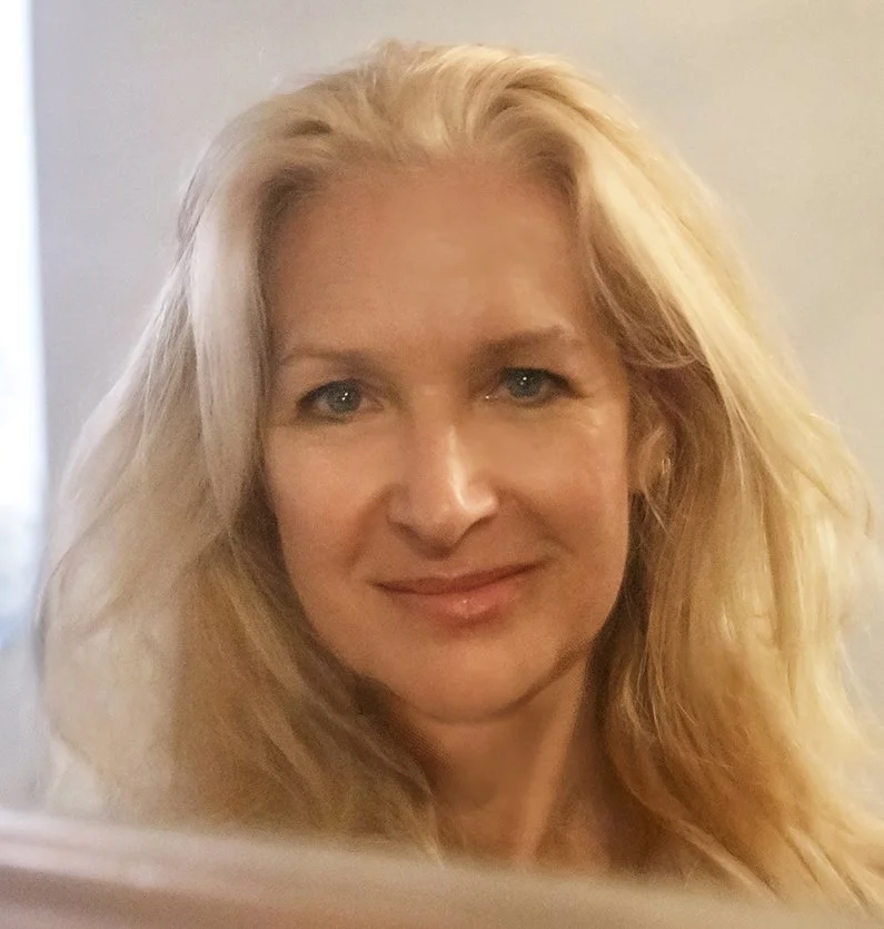 Close-up portrait of the owner of Sixth Sense Healing, a woman with long blonde hair smiling gently indoors.