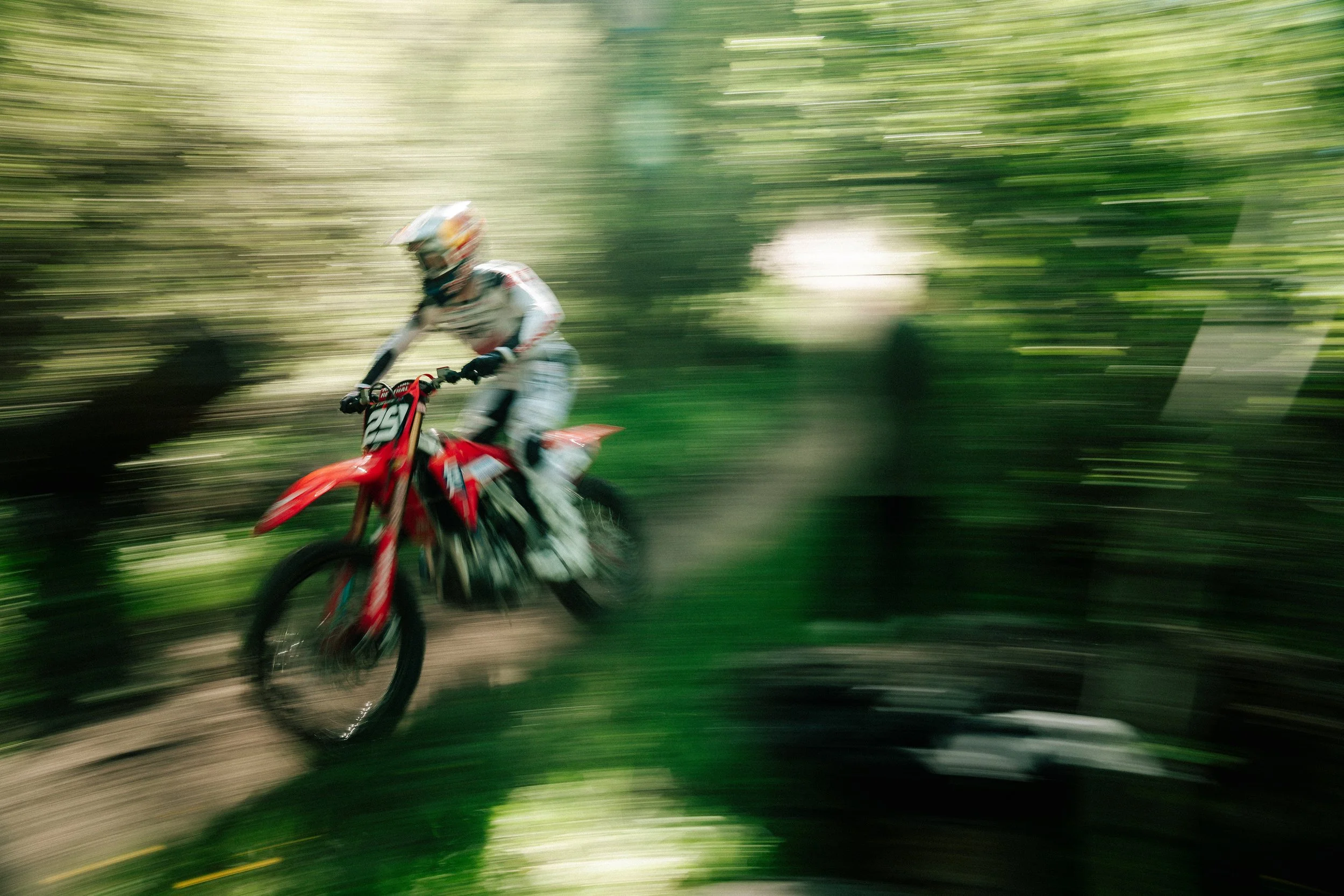 A person riding a mountain bike through a forest with motion blur indicating high speed.