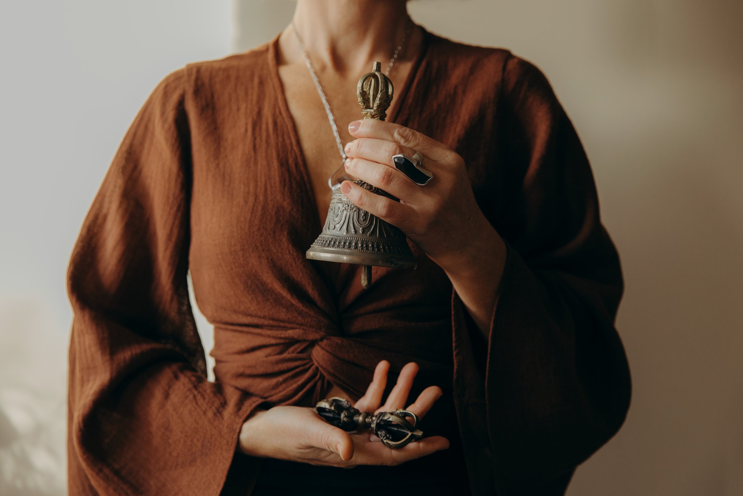 A person wearing a brown shirt holds a small ornate religious statue or figurine. The person's face is not visible.