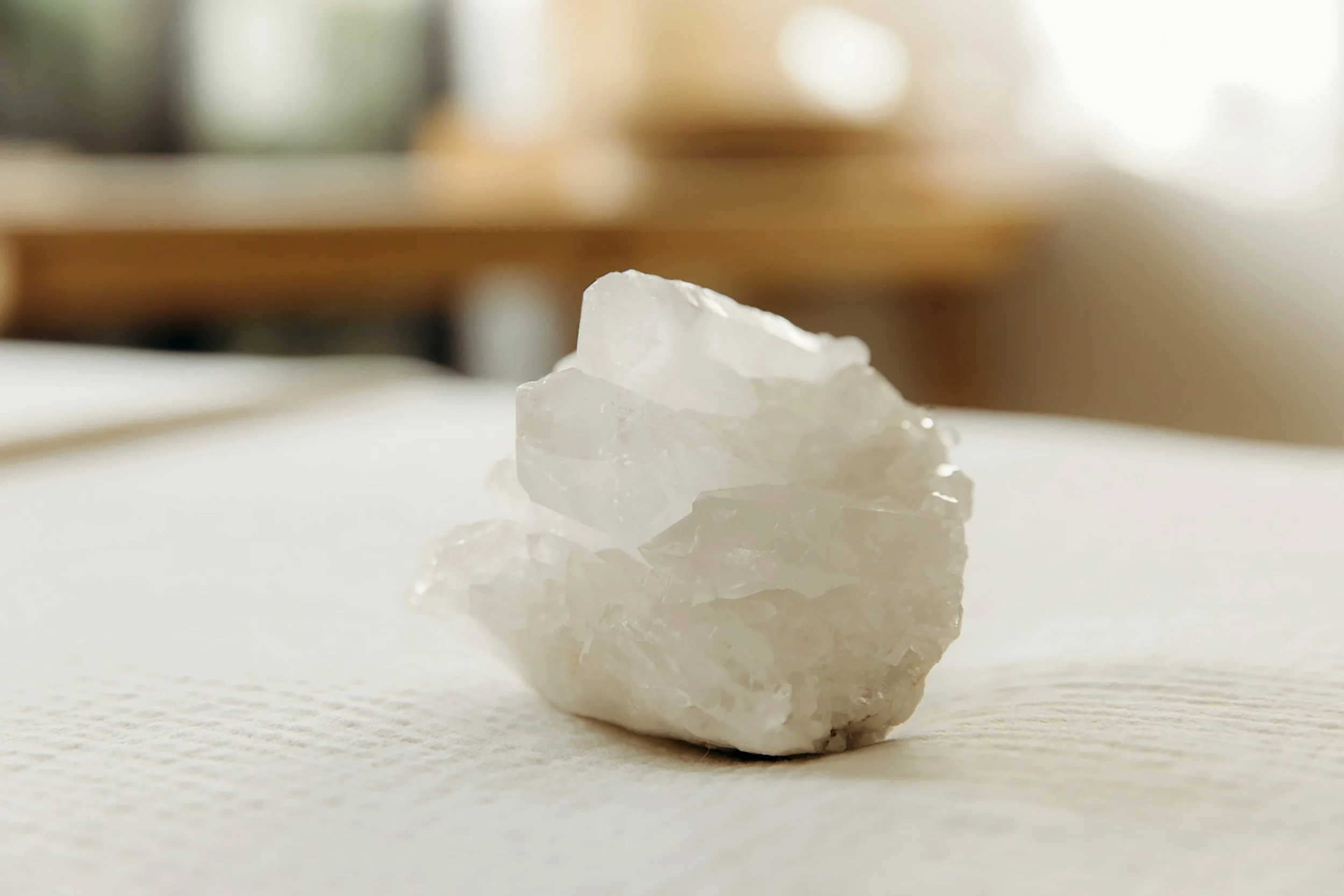 Close-up of a piece of white salt rock on a reflective surface. Blurred background with warm tones.