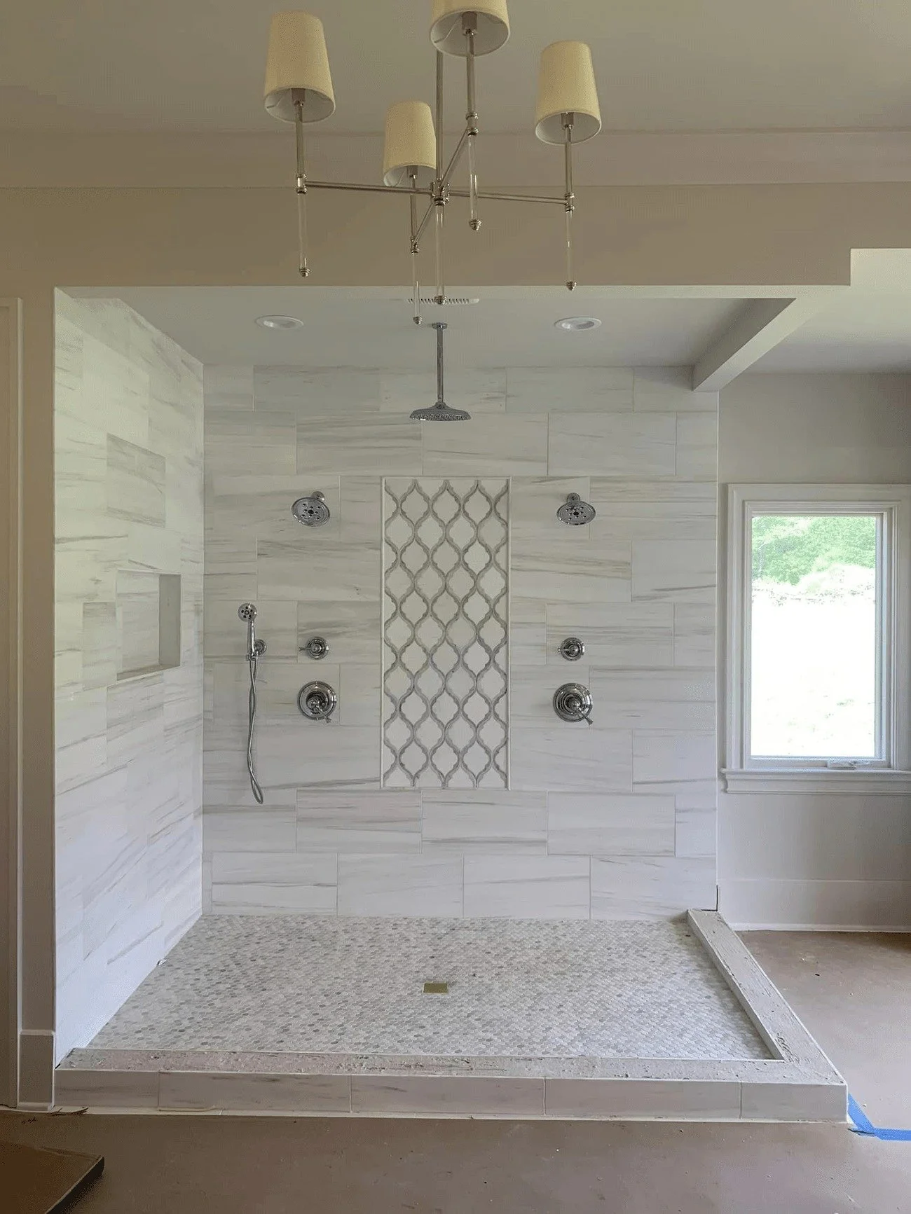 Newly renovated walk-in shower with multiple showerheads.