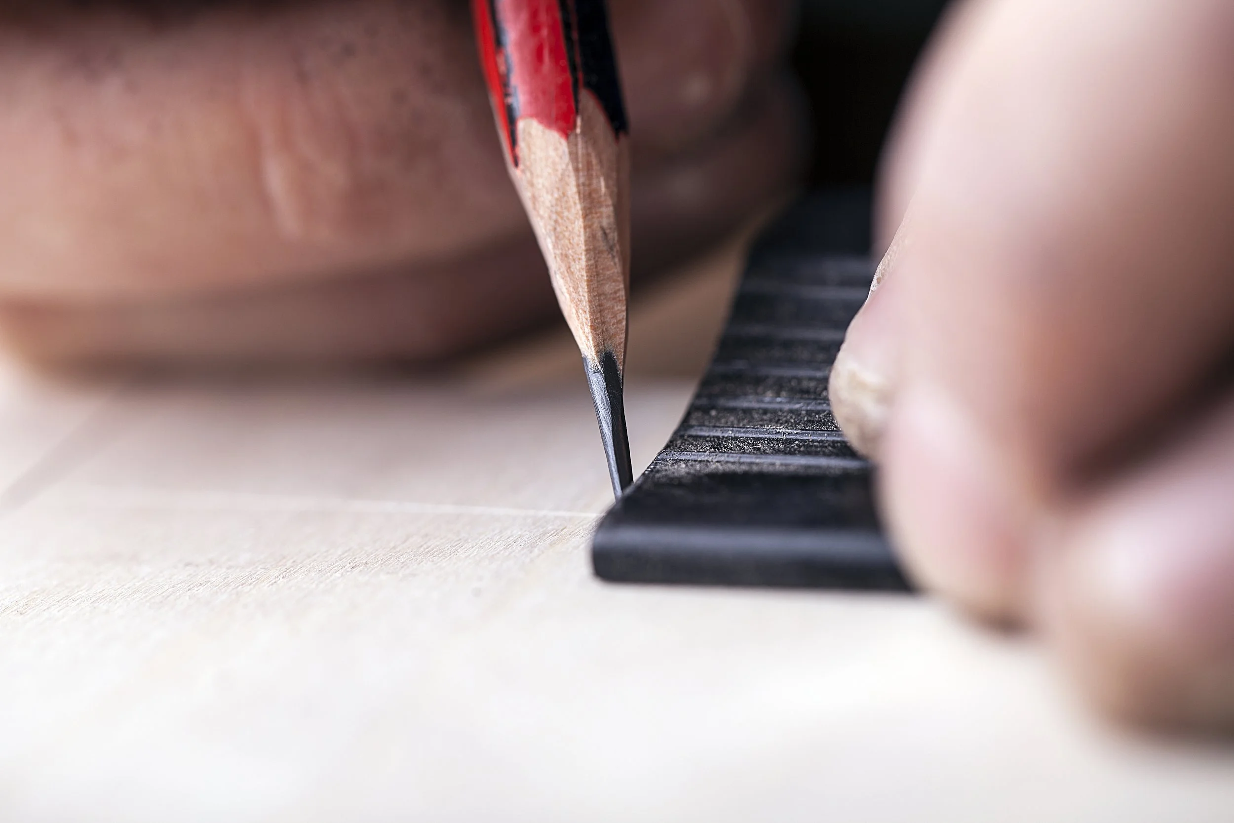 Close-up of a Nathan's hand with a pencil marking out dovetails on a drawer box sides, demonstrating detailed focus on the marking and measuring process.