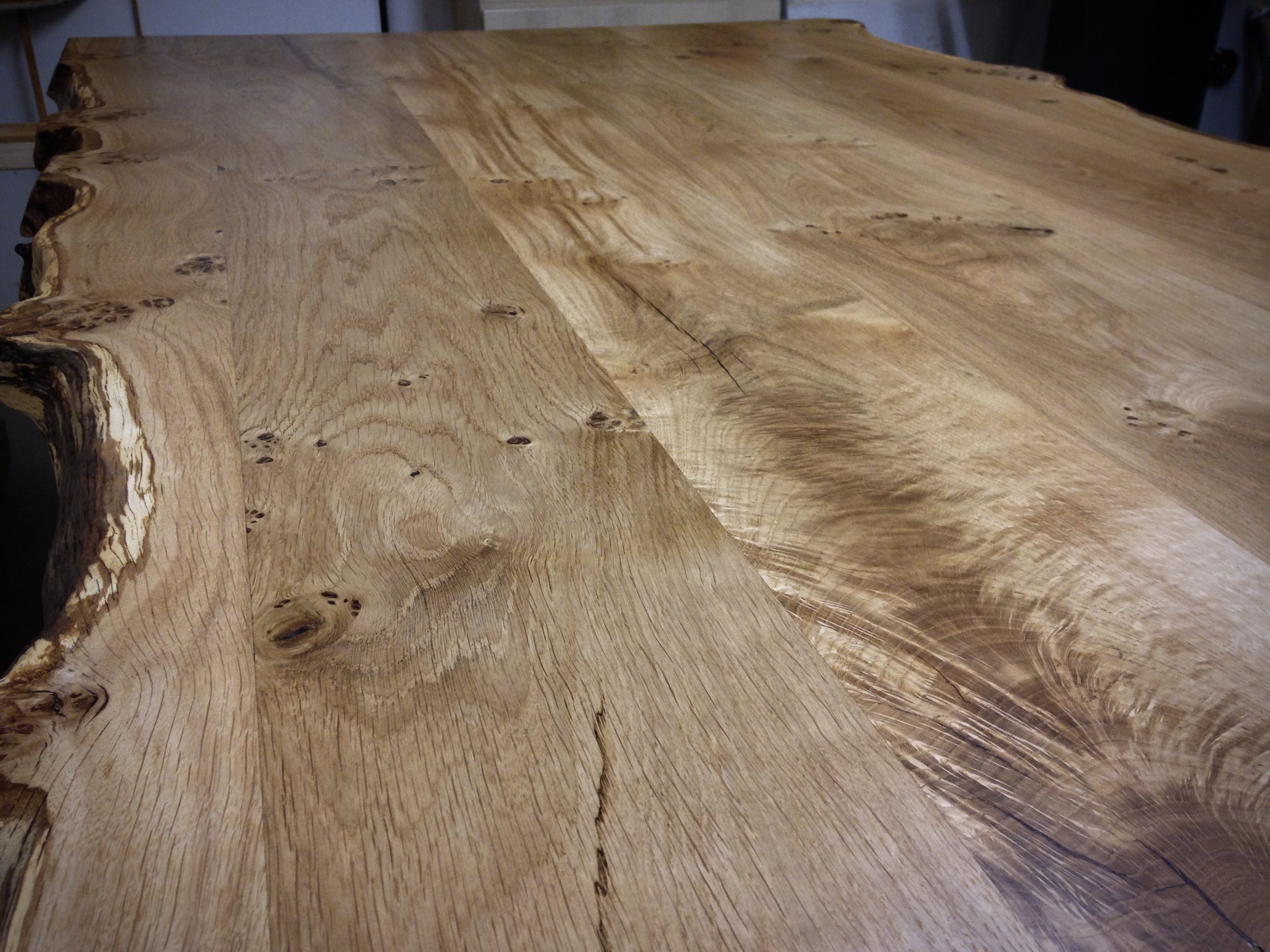 Close-up view of a natural wood table with a live edge, showcasing the wood grain, knots, and natural imperfections.