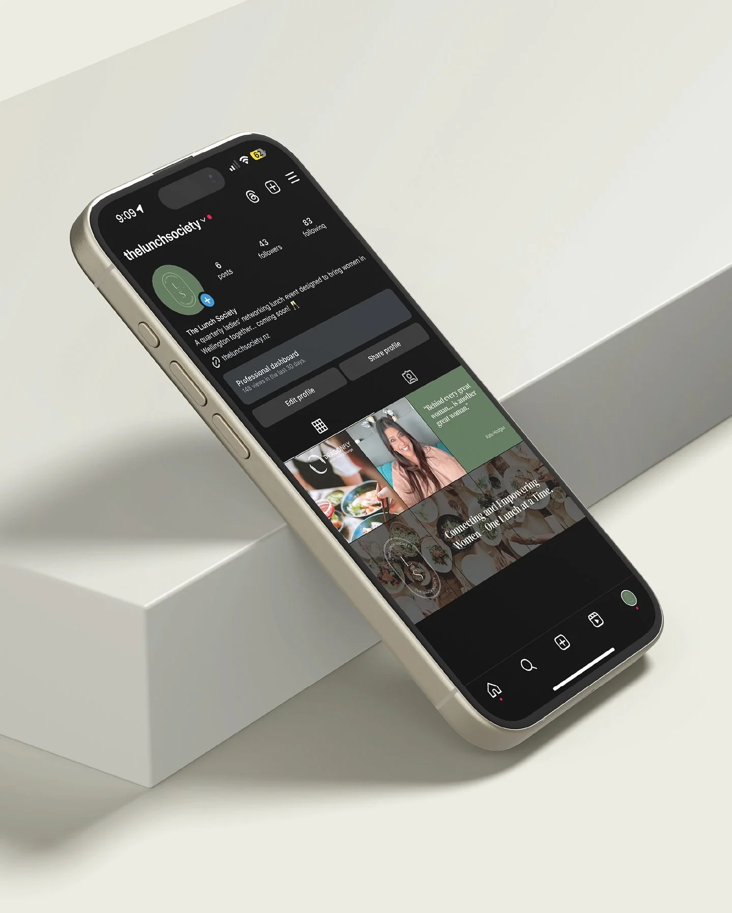 A smartphone displaying a social media profile page, placed on a white surface near a white box.