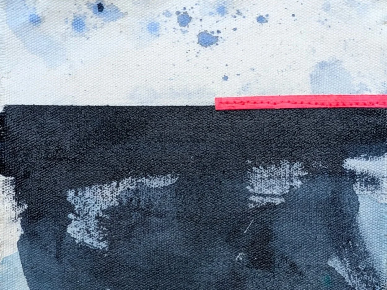 Close-up of a raw canvas colour study with indigo blue, white, and neon pink coloured strip of fabric, featuring a horizontal deep blue horizon, some blue splatter marks, and pink stitching.