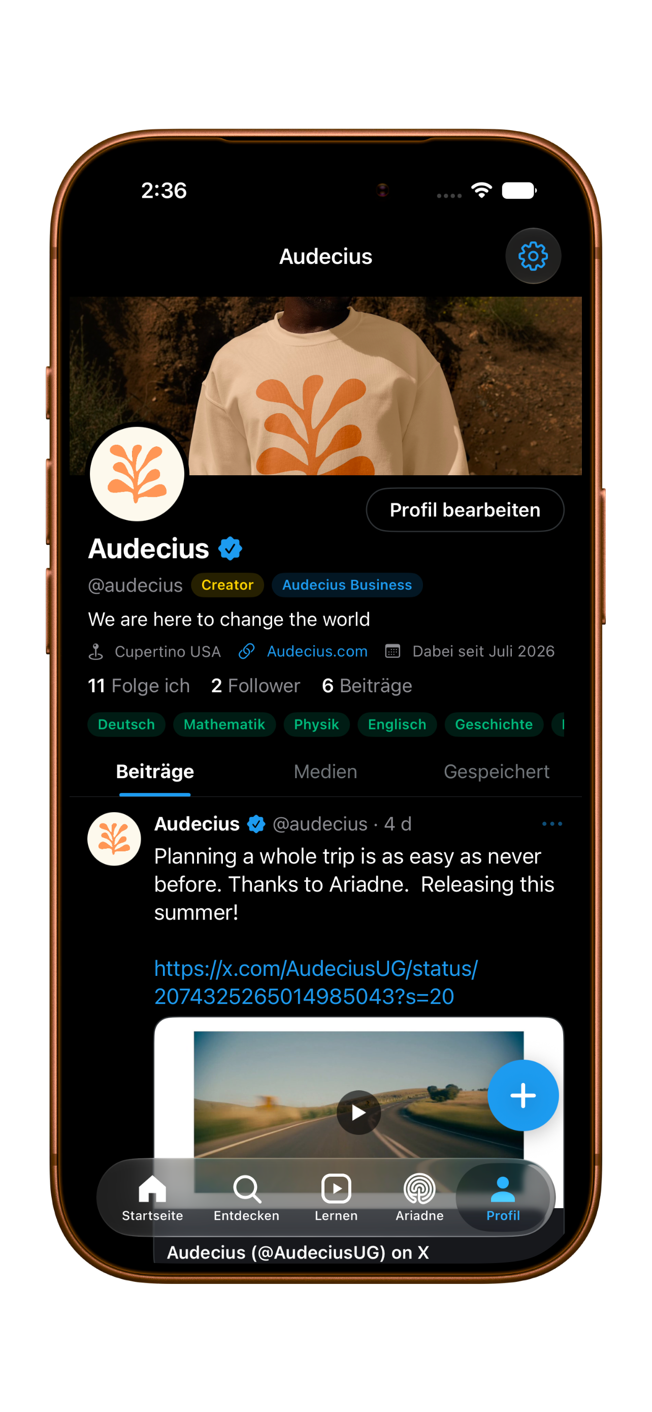 A smartphone screen displaying a social media profile named Audecius, featuring a profile picture of an orange leaf-like symbol on a white background, a cover photo of a person wearing a white sweatshirt with an orange design, and various social media details including bio, location, website, and recent posts.