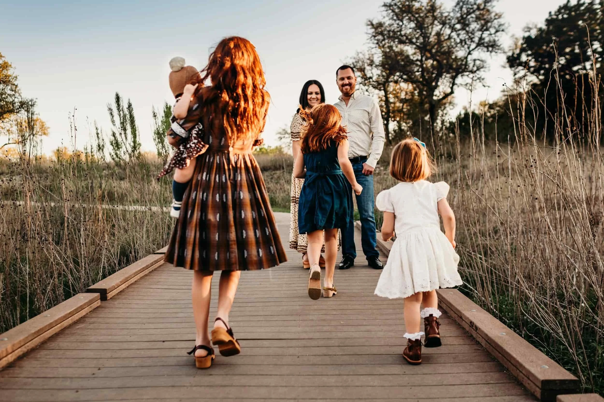 A family of six enjoys a sunset stroll on a wooden path, smiling together—just like trust built with your Medicare Insurance Agency.