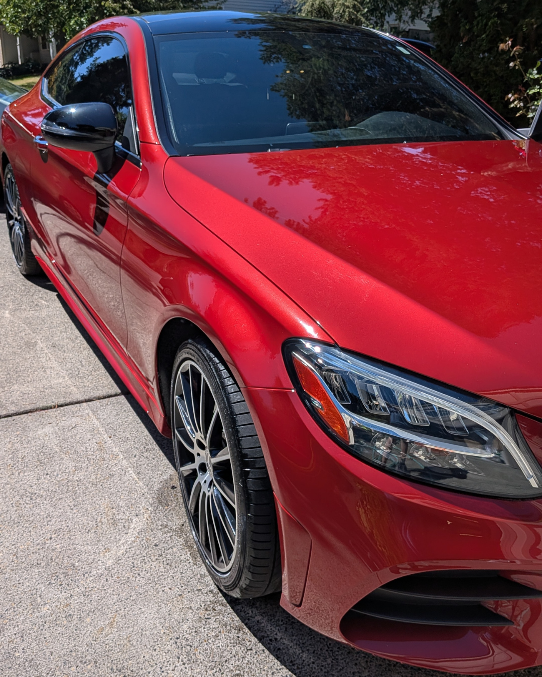 A shiny red Mercedes-Benz parked on a concrete driveway.