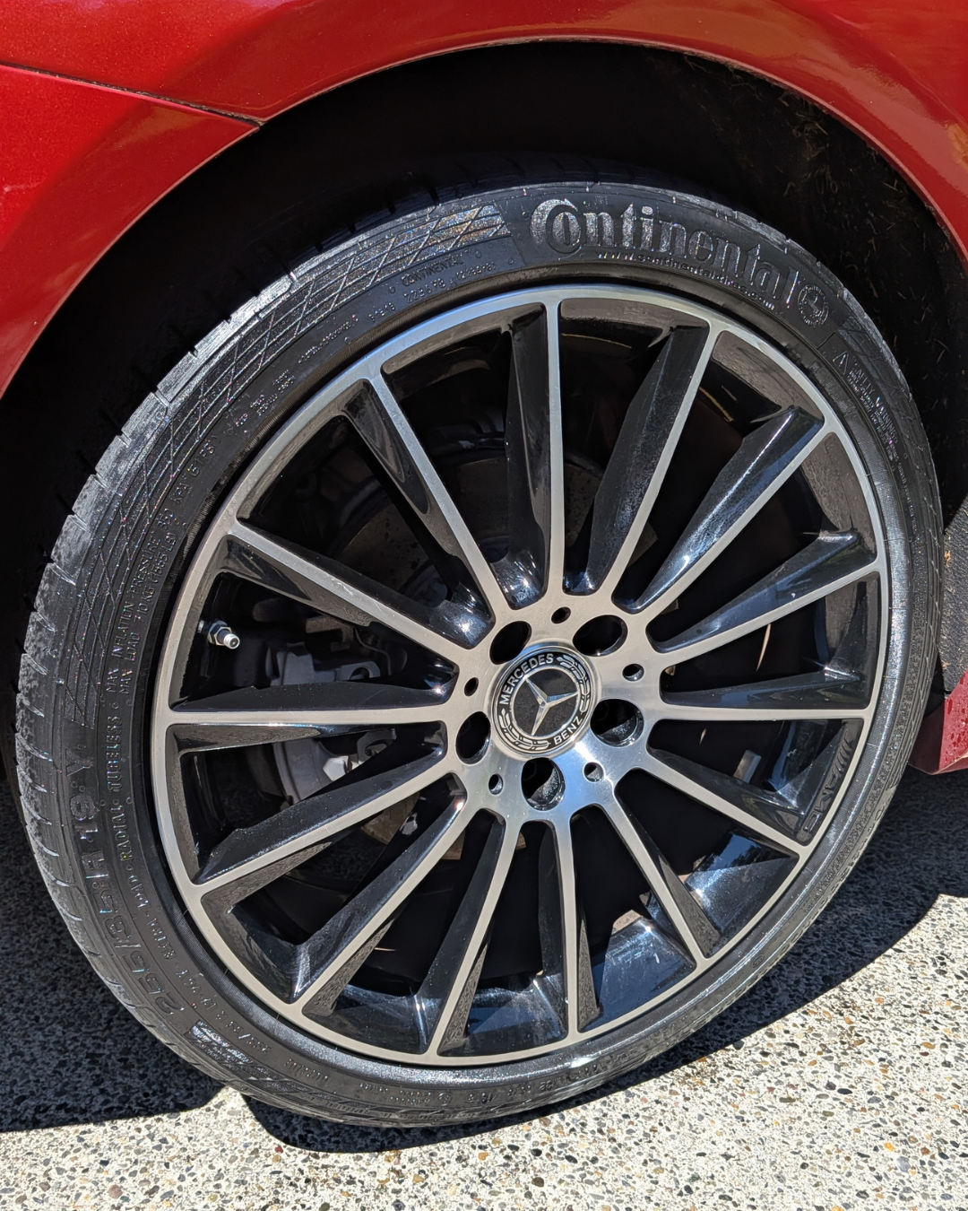 Close-up of a red Mercedes-Benz car wheel with a multi-spoke alloy rim and a Continental tire.