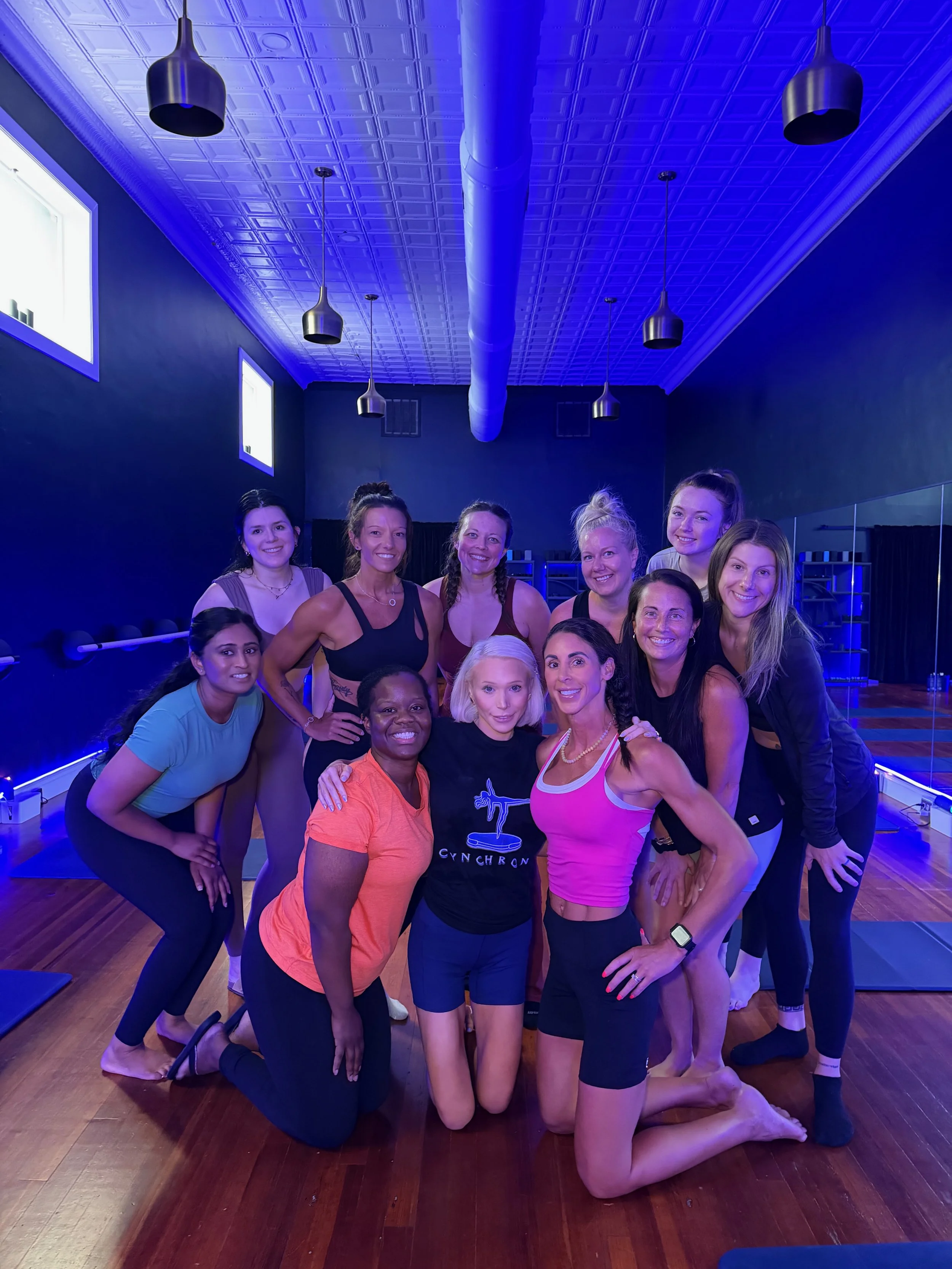 Cynchrony Womens' Wellness mat Pilates class with women/girls smiling after a fitness and Pilates workout in the Cynchrony Womens' Wellness Concord, NC and Cabarrus County Pilates, yoga, and barre studio.
