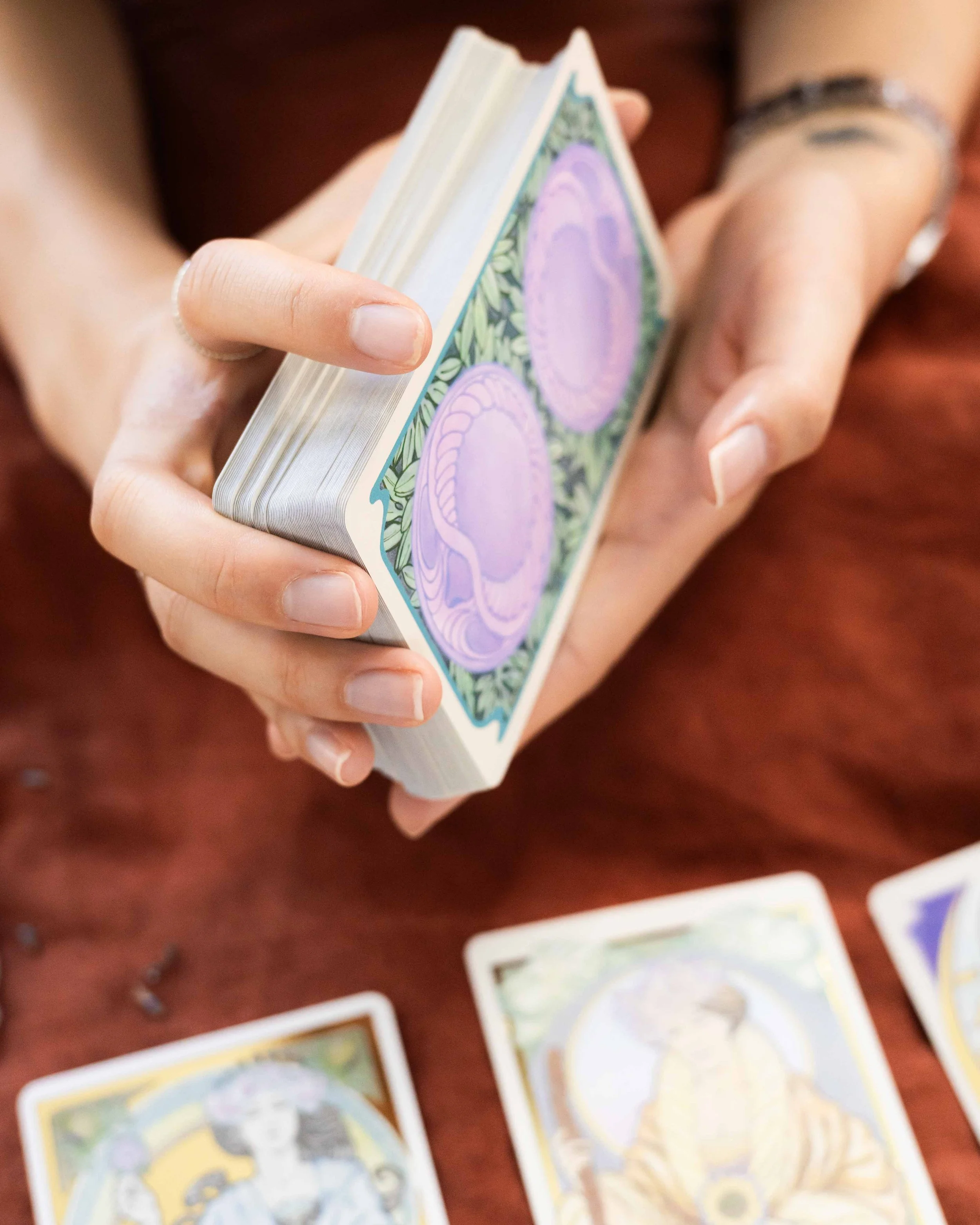 Hands shuffling a tarot deck, with cards laid out nearby.