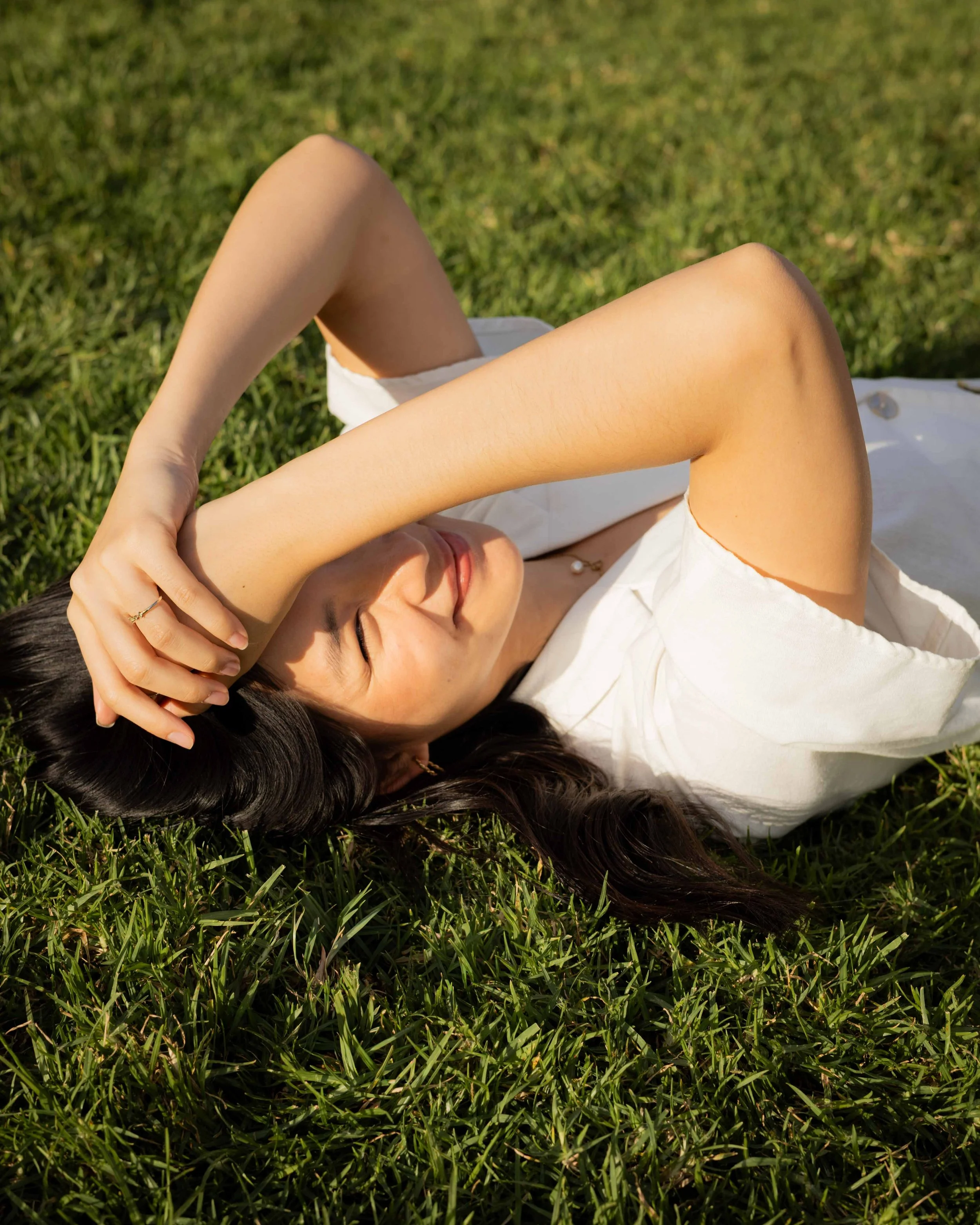 Olivia Lei lying in the grass, smiling at the camera.