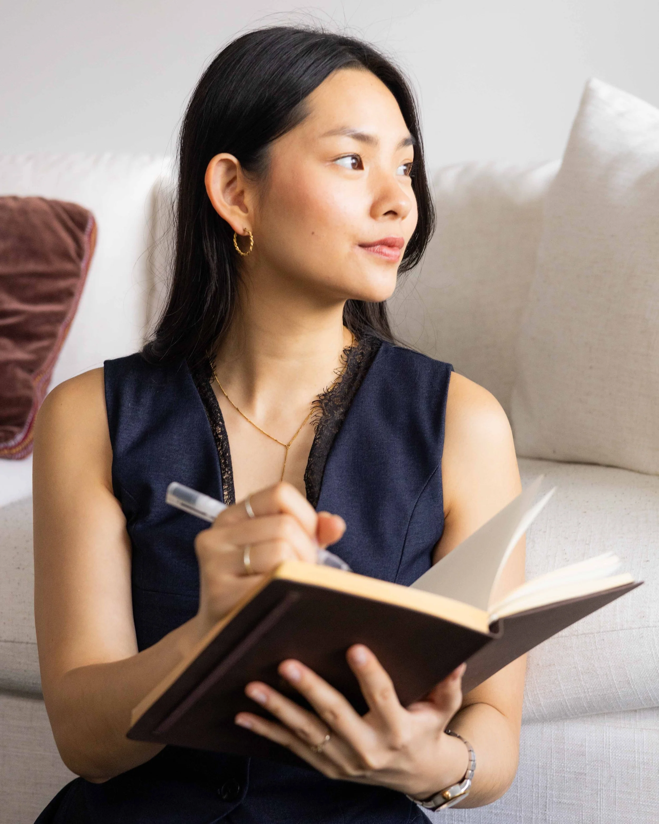 Olivia Lei sitting with a journal, looking thoughtful.