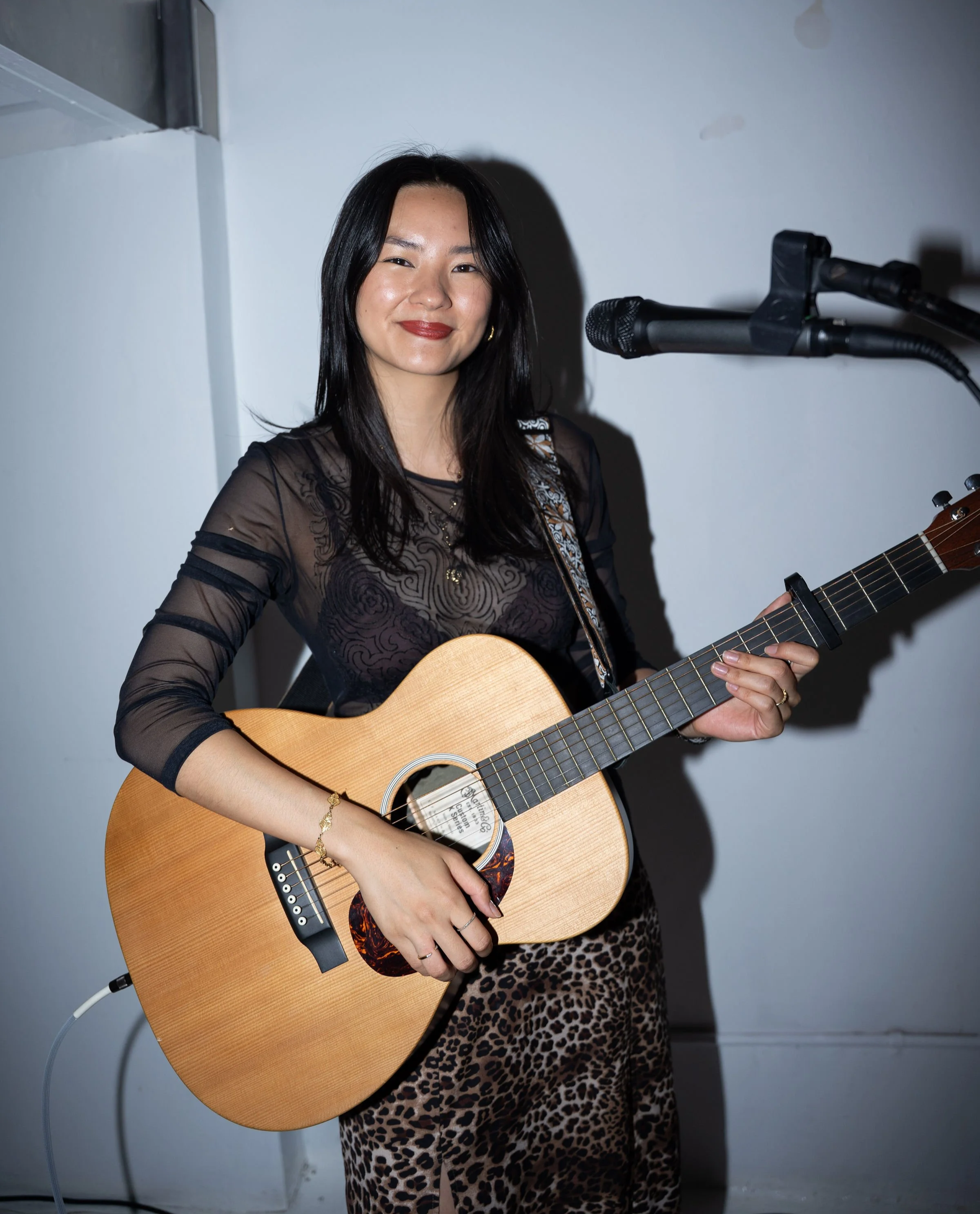 Olivia Lei performing with a guitar at the microphone.