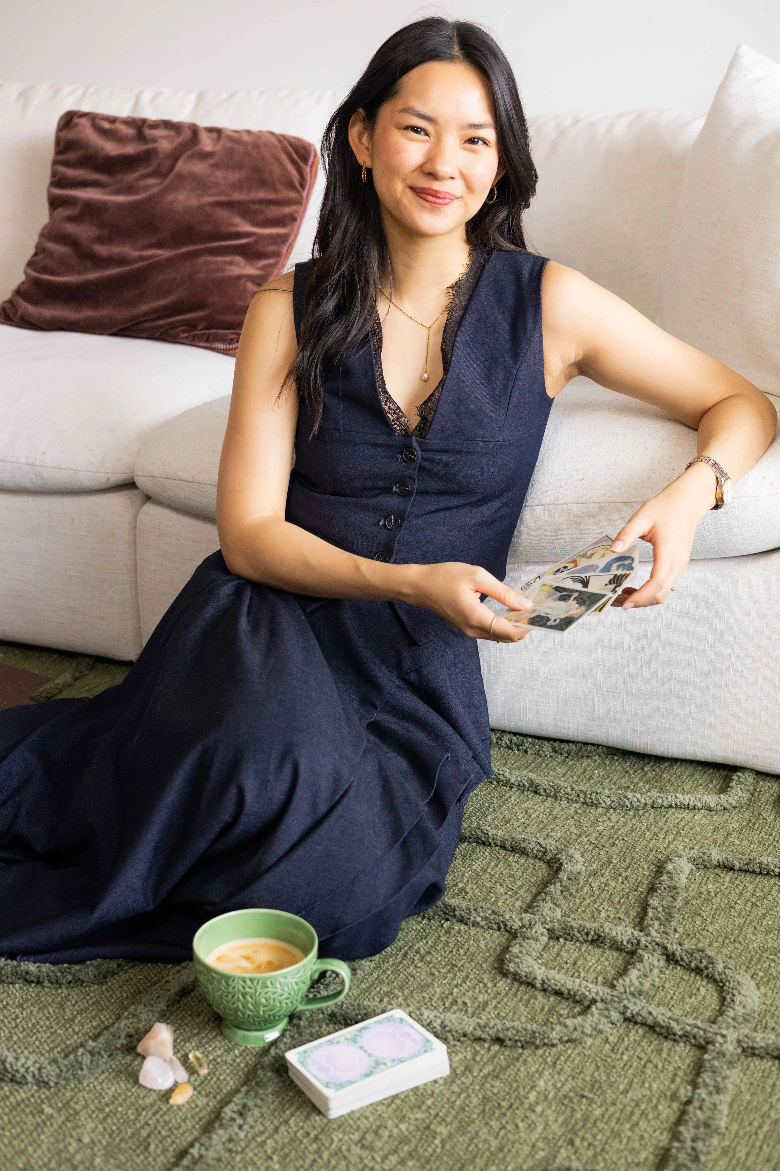 Olivia Lei smiling while holding tarot cards, sitting on the floor during a psychic reading.