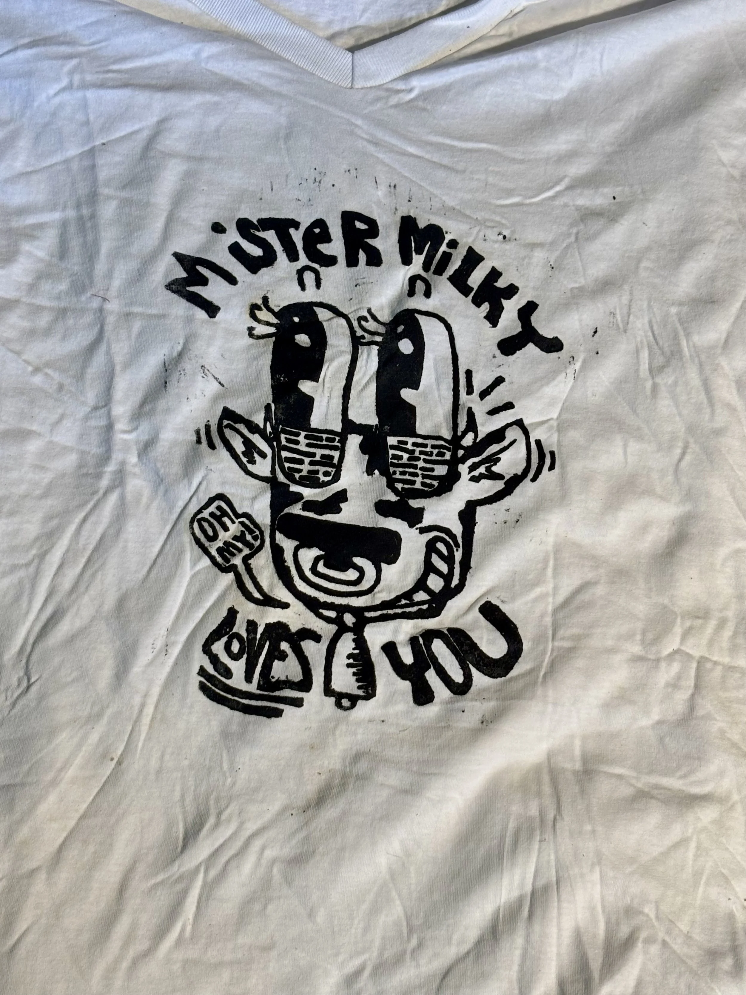 A t shirt with a printed design featuring a cartoon cow, with the words "MISTER MILKY" above the cartoon and the words "LOVES YOU" below.