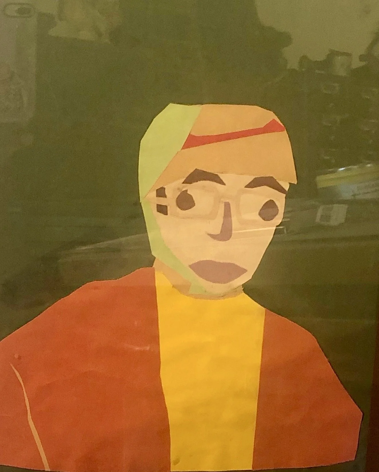 A paper lantern with a painting of a person's face and upper torso, including orange hair, glasses, and an orange and yellow outfit, with a dark background.