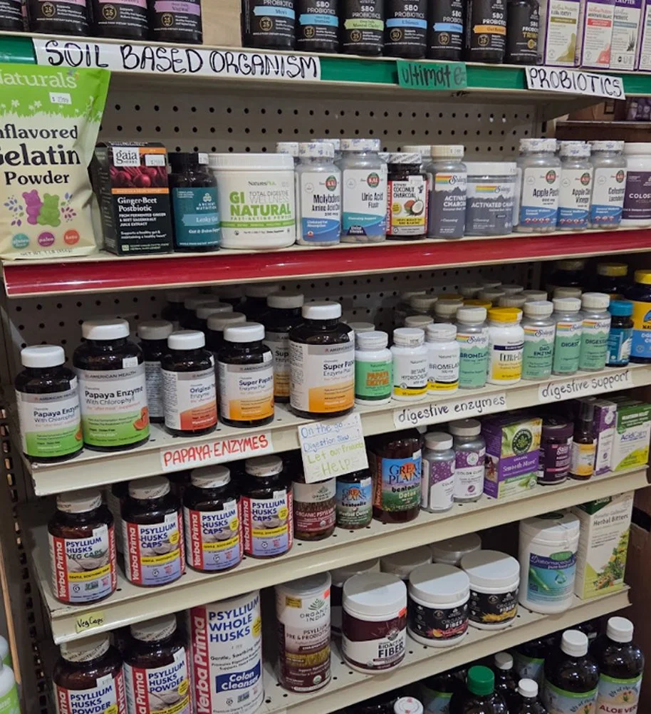 Shelves stocked with dietary supplements, probiotics, digestive enzymes, and herbal health products in a health store.