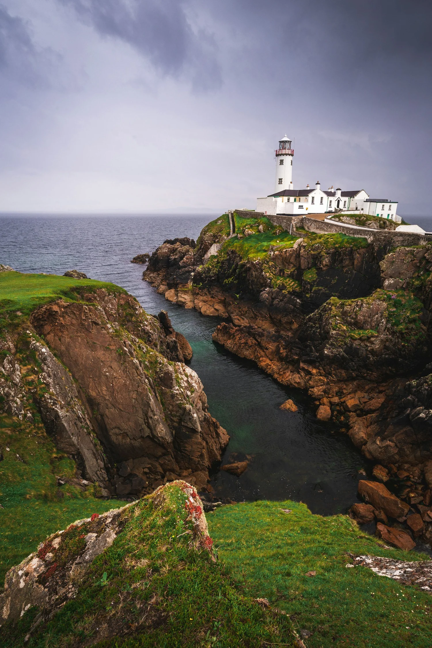 A white lighthouse above a rocky Atlantic inlet on Ireland's coast