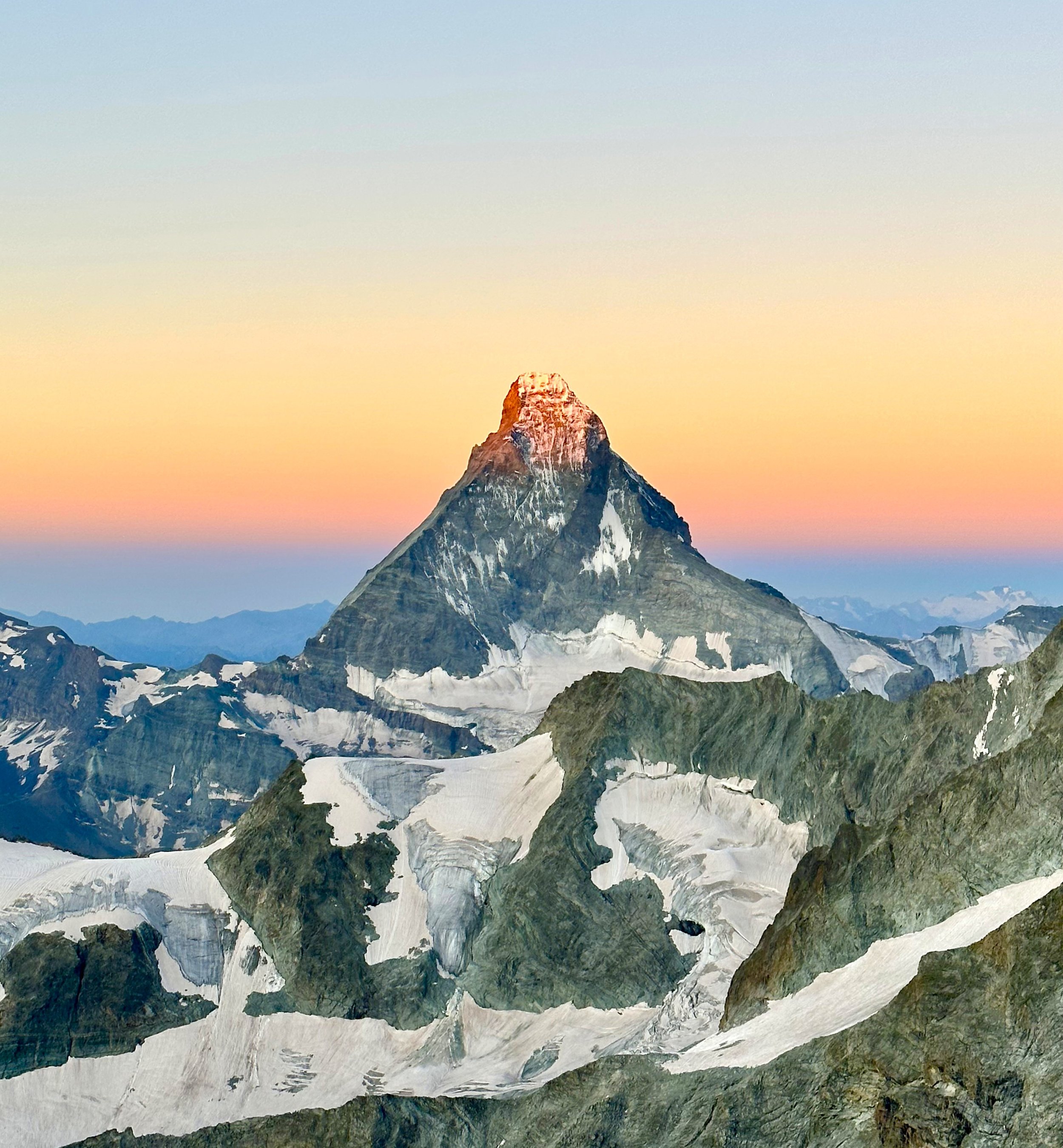Matterhorn with snow-capped peaks  around at sunrise, with a colorful sky in the background of Zermatt.
