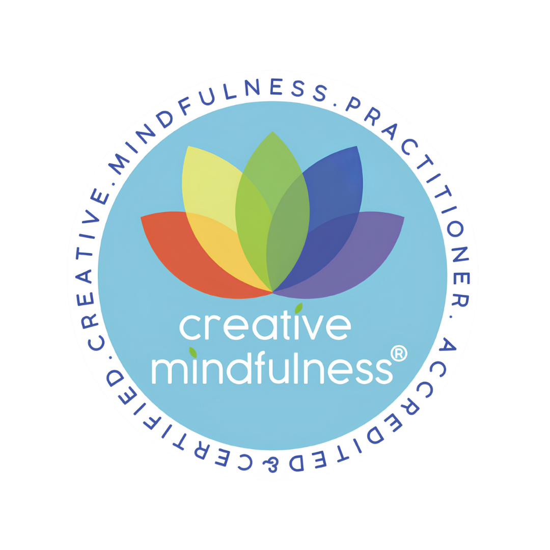 A circular logo for Creative Mindfulness featuring a multi-colored lotus flower with seven petals, with the words 'creative mindfulness' in lowercase and a small green leaf dotting the 'i's. Around the outer edge are the words 'created, directed, active, mindful, practitioner,'.